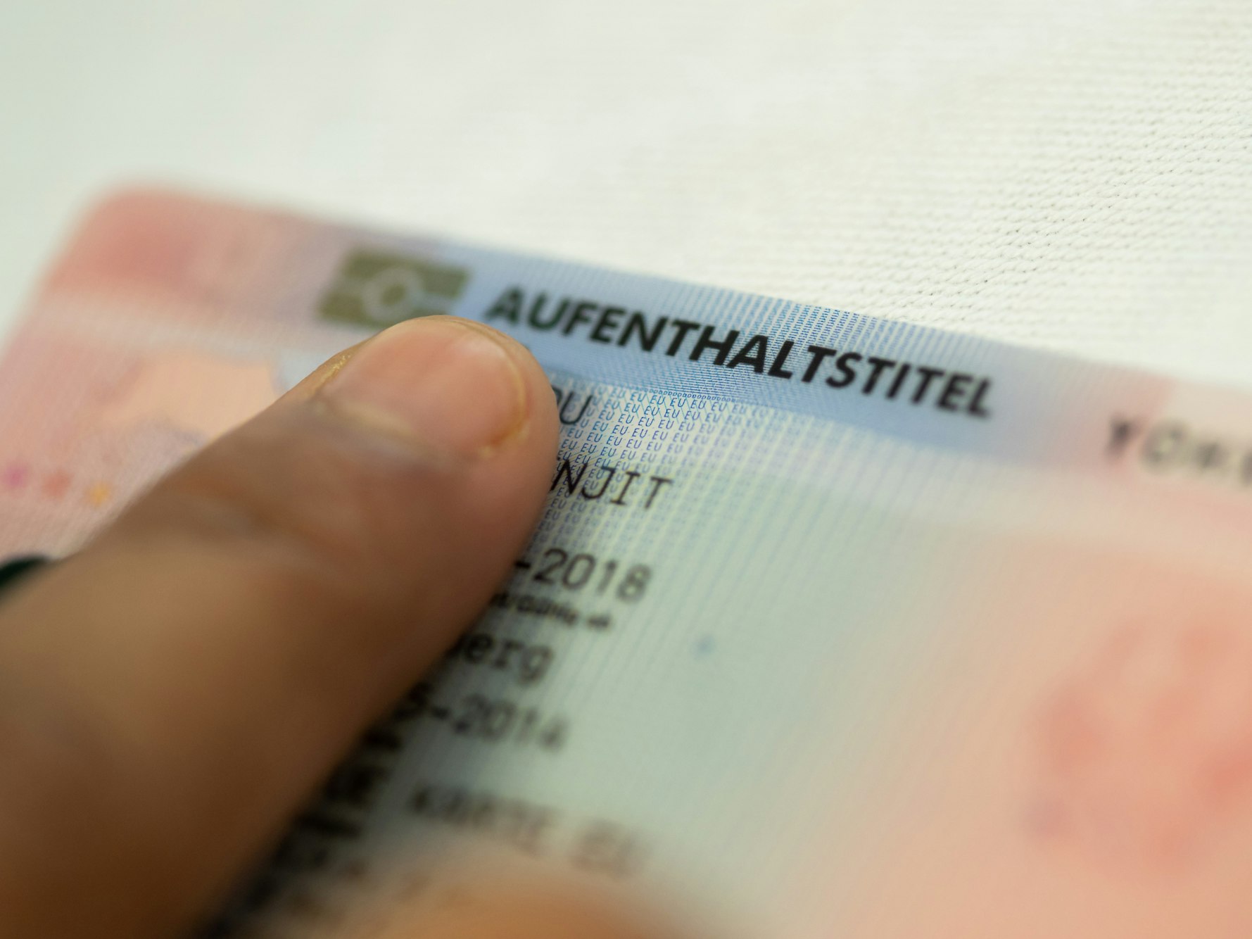Eine Person hält einen Aufenthaltstitel in der Hand.