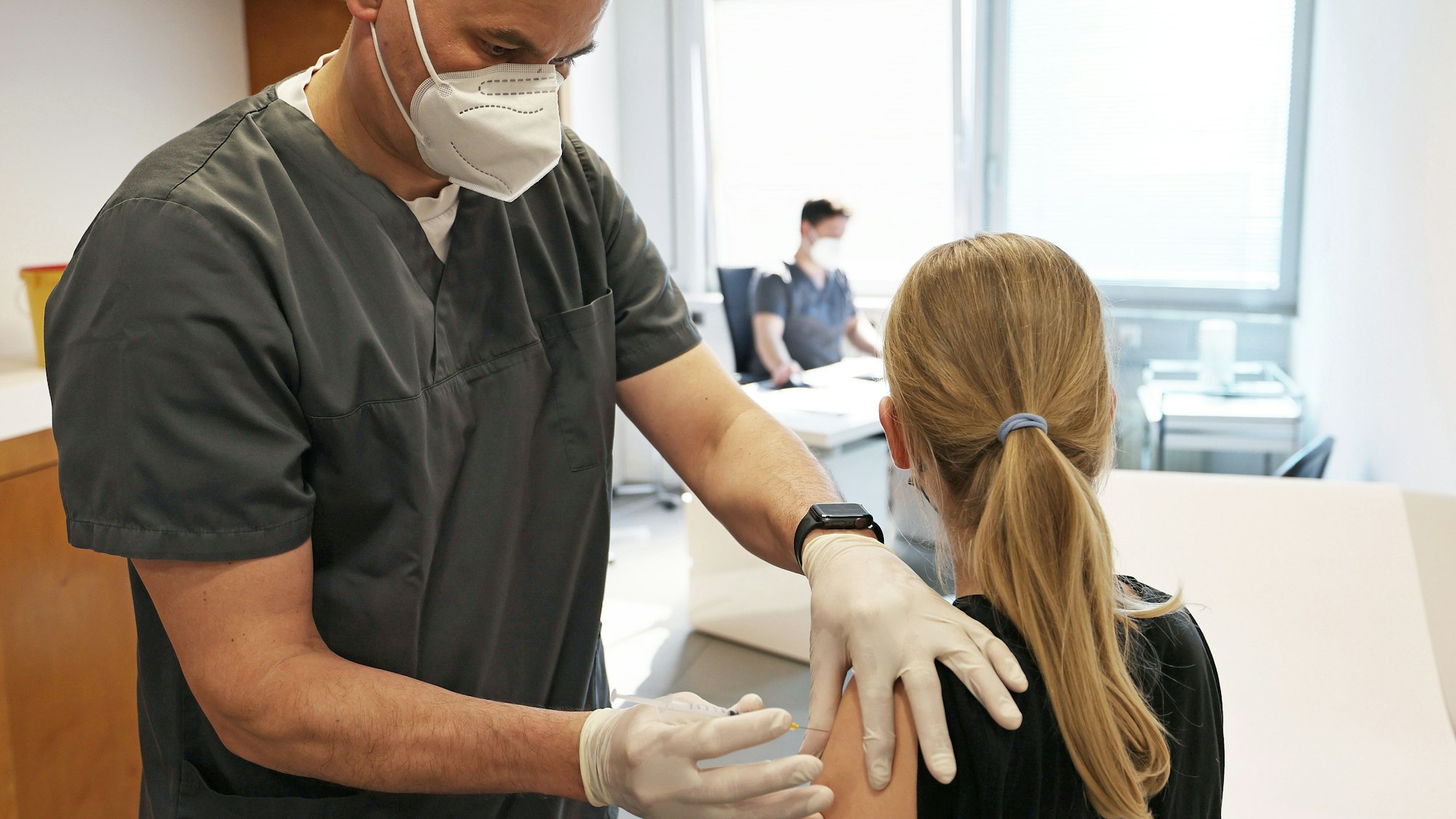 Ein zwölfjähriges Mädchen wird in einer Arztpraxis von dem Hausarzt Tim Koop (l) mit dem Serum von Biontech/Pfizer geimpft.