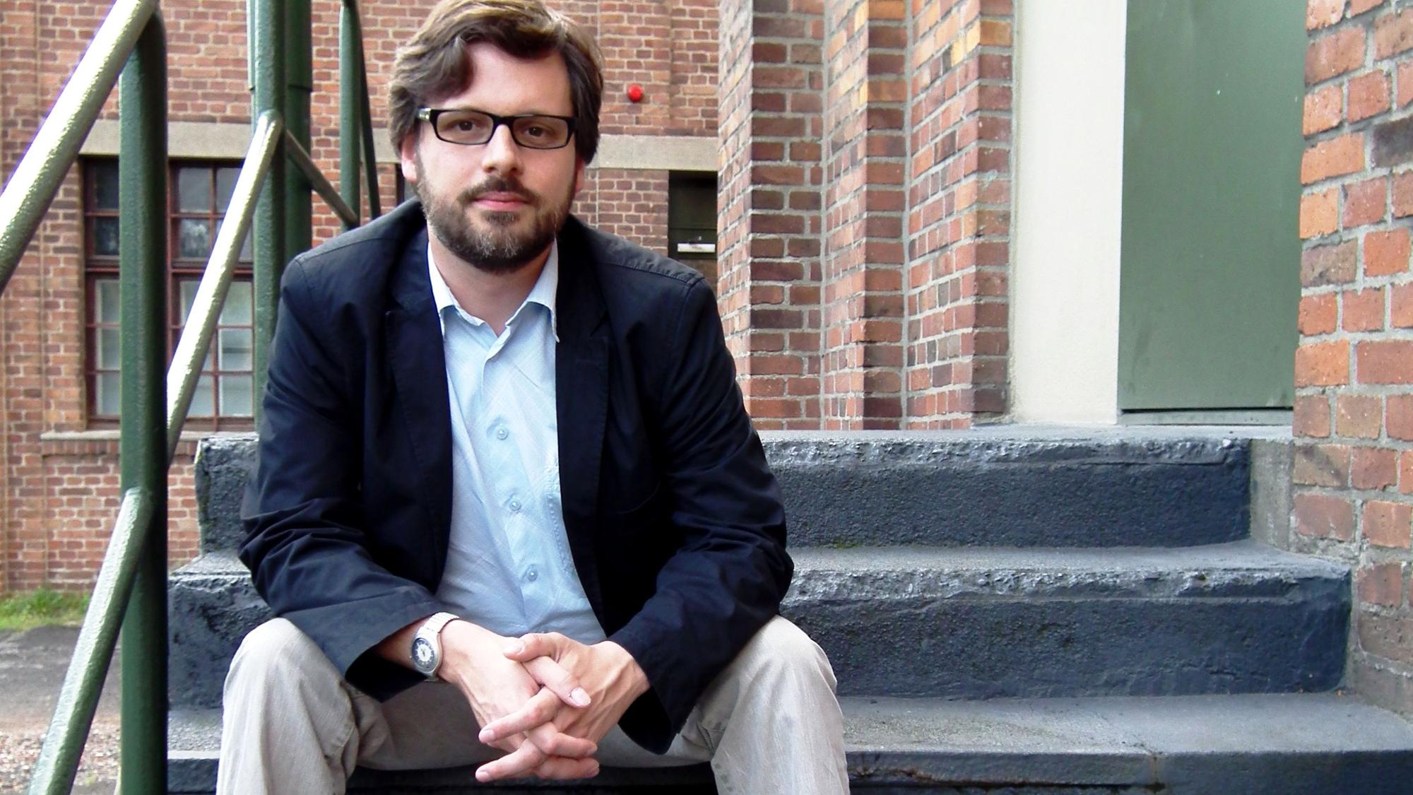 Sebastian Bartoschek (38) sitzt auf einer Treppenstufe.