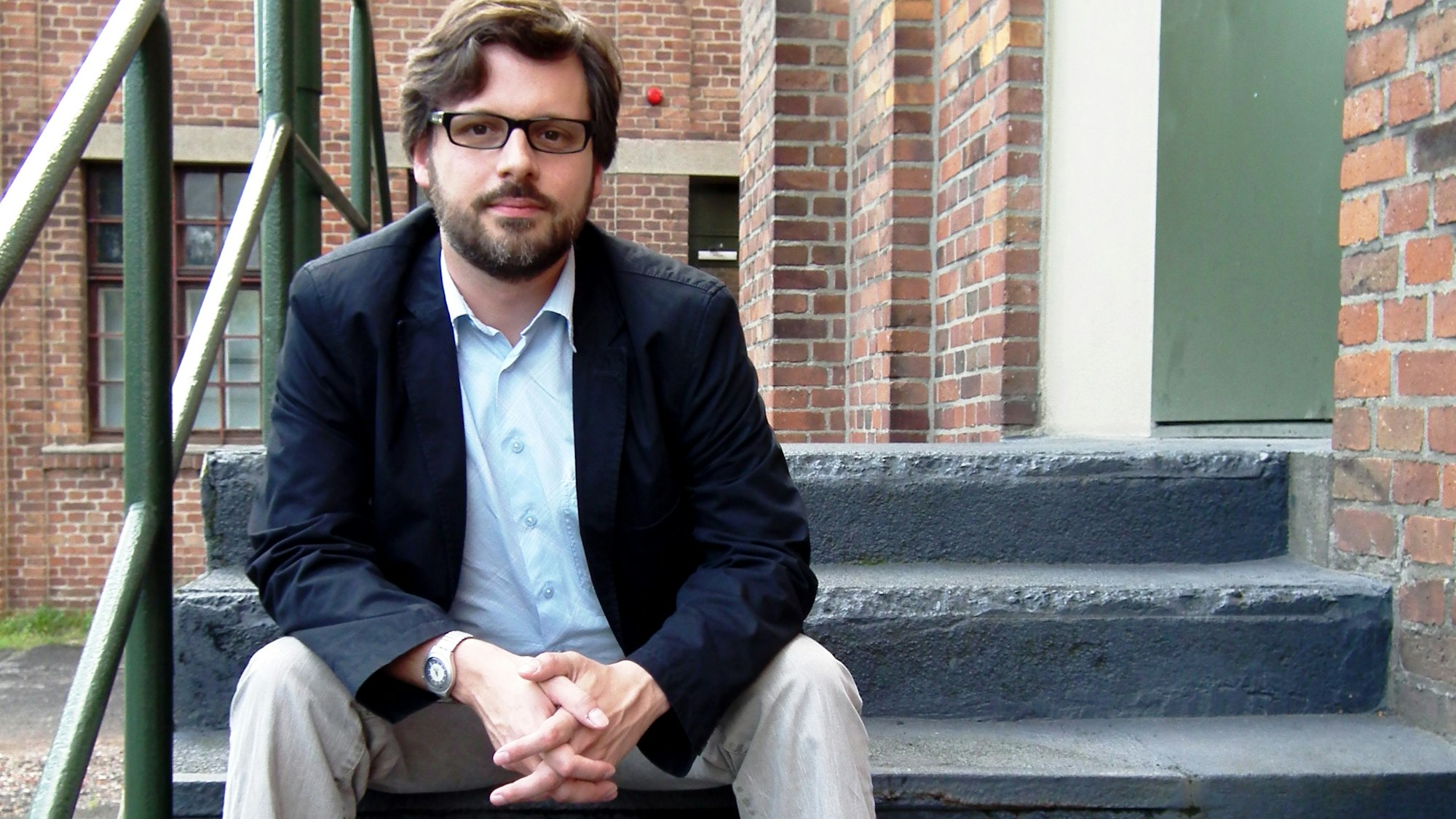 Sebastian Bartoschek (38) sitzt auf einer Treppenstufe.