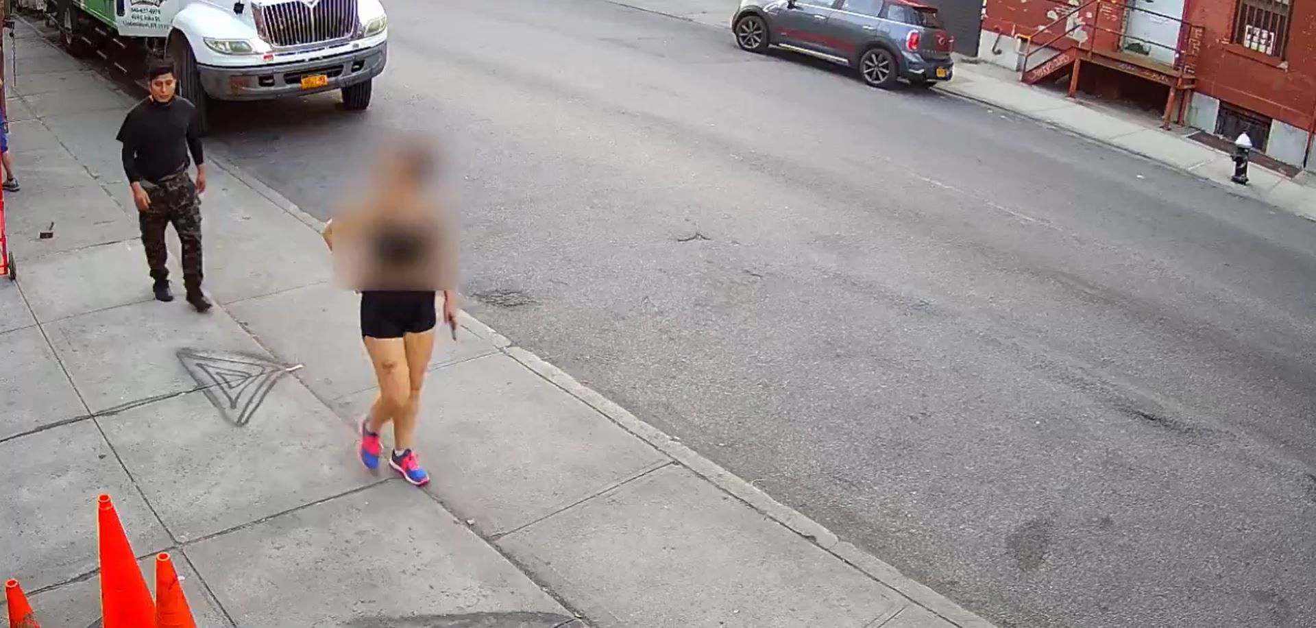 Ein Screenshot aus dem Video einer Überwachungskamera zeigt einen Mann, der direkt hinter einer Frau auf einem Bürgersteig entlangläuft. Die New Yorker Polizei sucht den Mann, weil er die Frau sexuell angegriffen hatte.