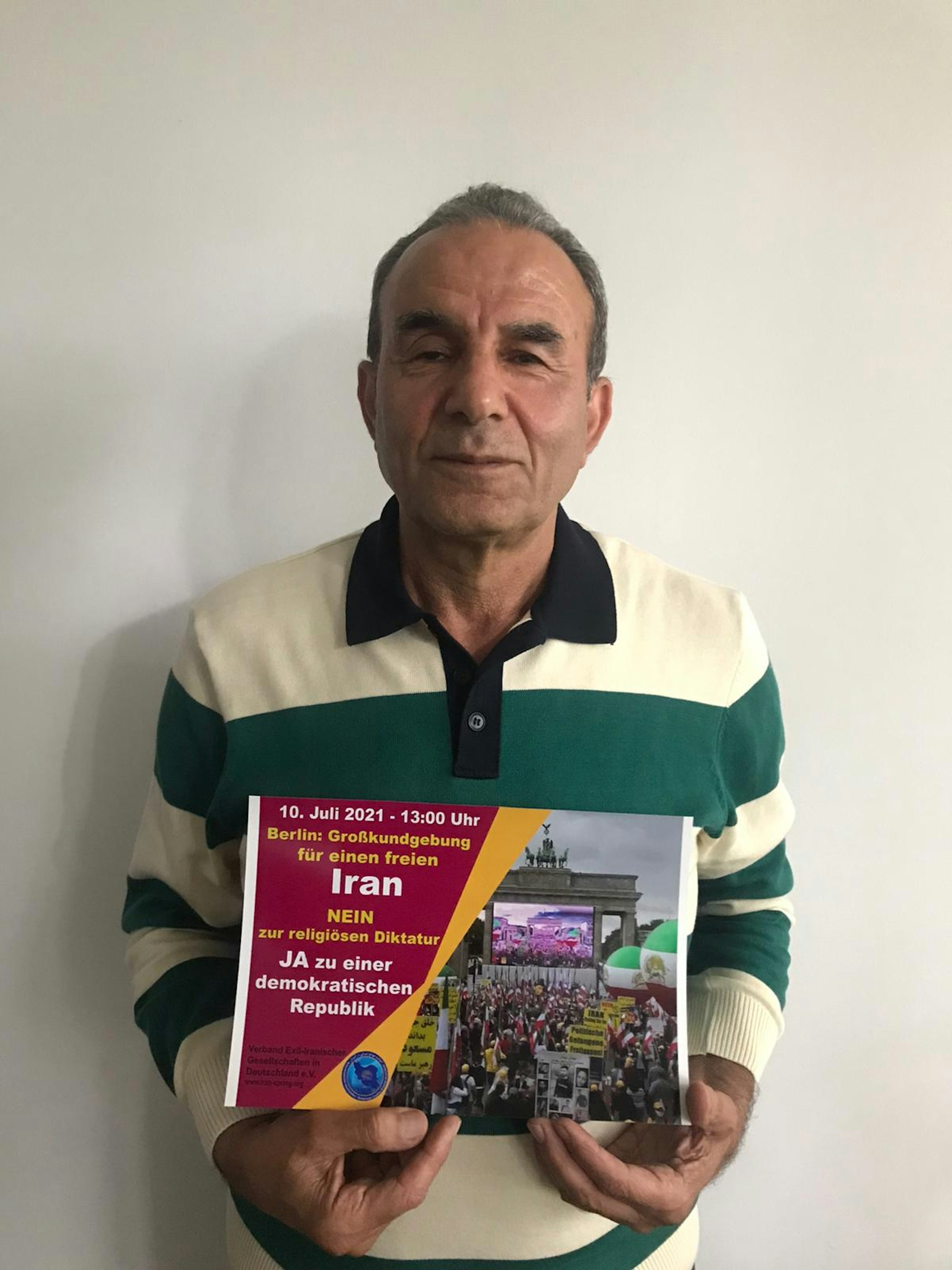 Der Kölner Taxi-Fahrer Ali Sajadi hält ein Plakat mit Bezug auf die Demo gegen den iranischen Präsidenten Ebrahim Raisi am 10. Juli in Berlin.