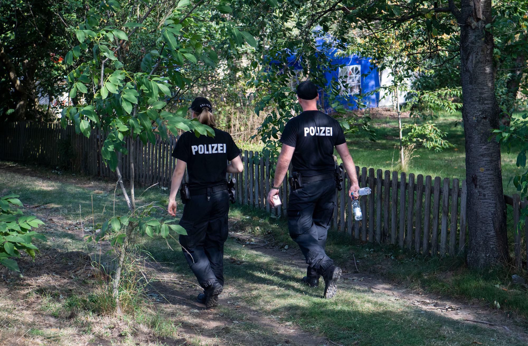 Zwei Polizisten sind in einer Kleingartenanlage unterwegs.