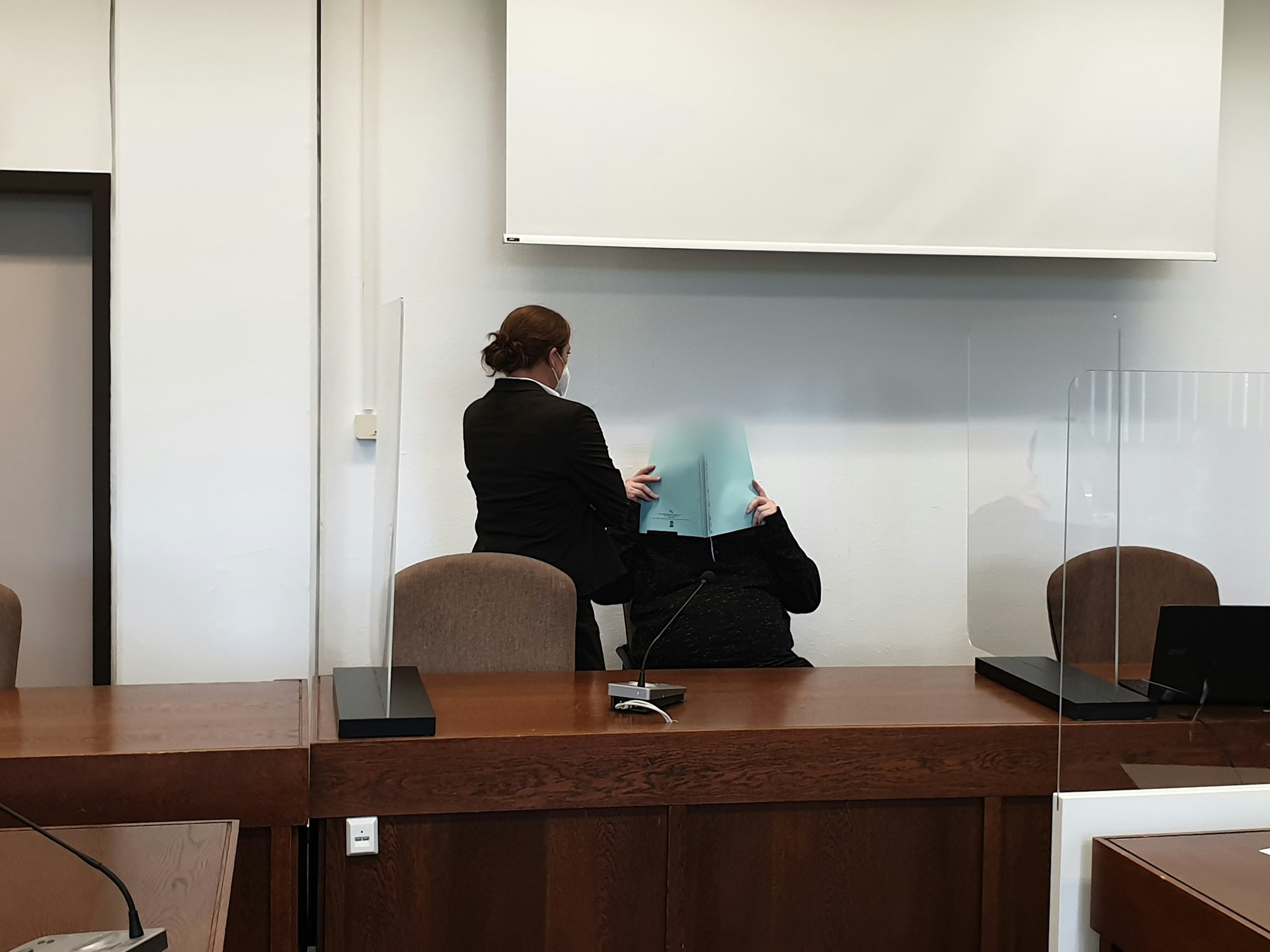 Vor dem Kölner Landgericht hält sich der Angeklagte eine Akte vor sein Gesicht.