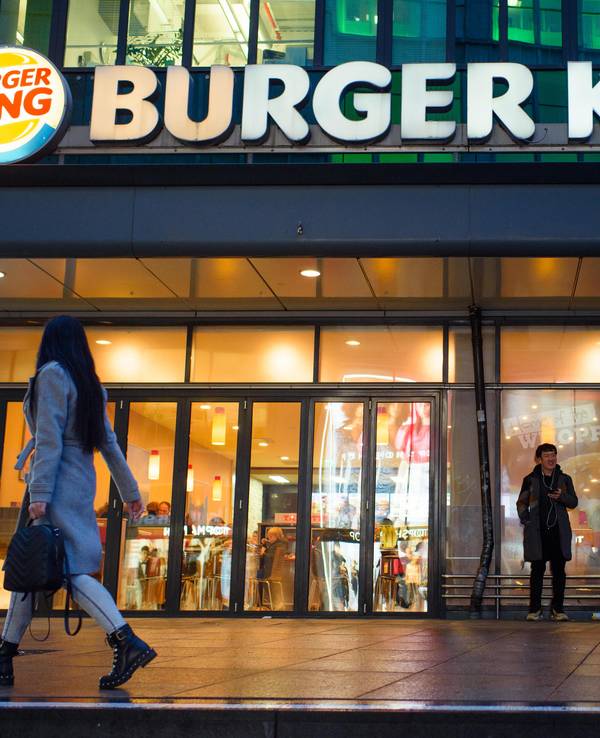 Passanten und Passantinnen gehen am Abend an einer Burger King-Filiale auf dem Alexanderplatz in Berlin vorbei.