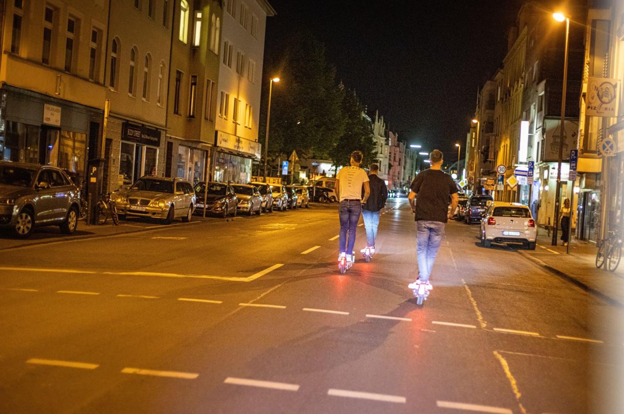 Drei junge Männer fahren mit E-Scootern in Köln-Sülz.