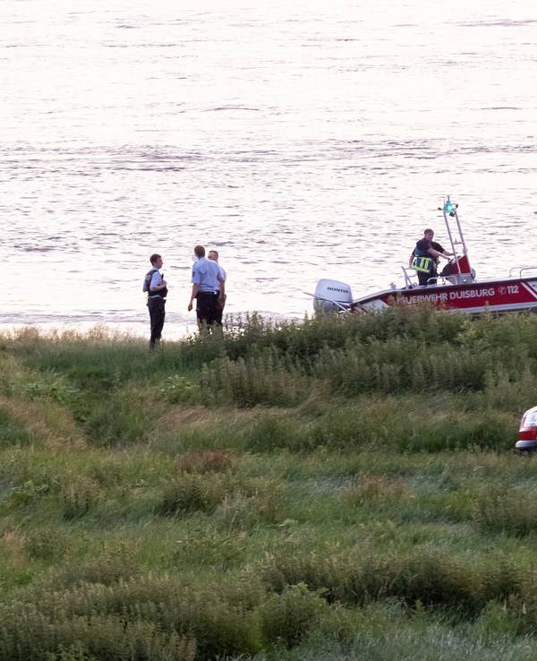 Einsatzkräfte der Polizei, Feuerwehr und DLRG arbeiten am Ufer des Rheins. Auch ein Rettungsboot ist im Einsatz.