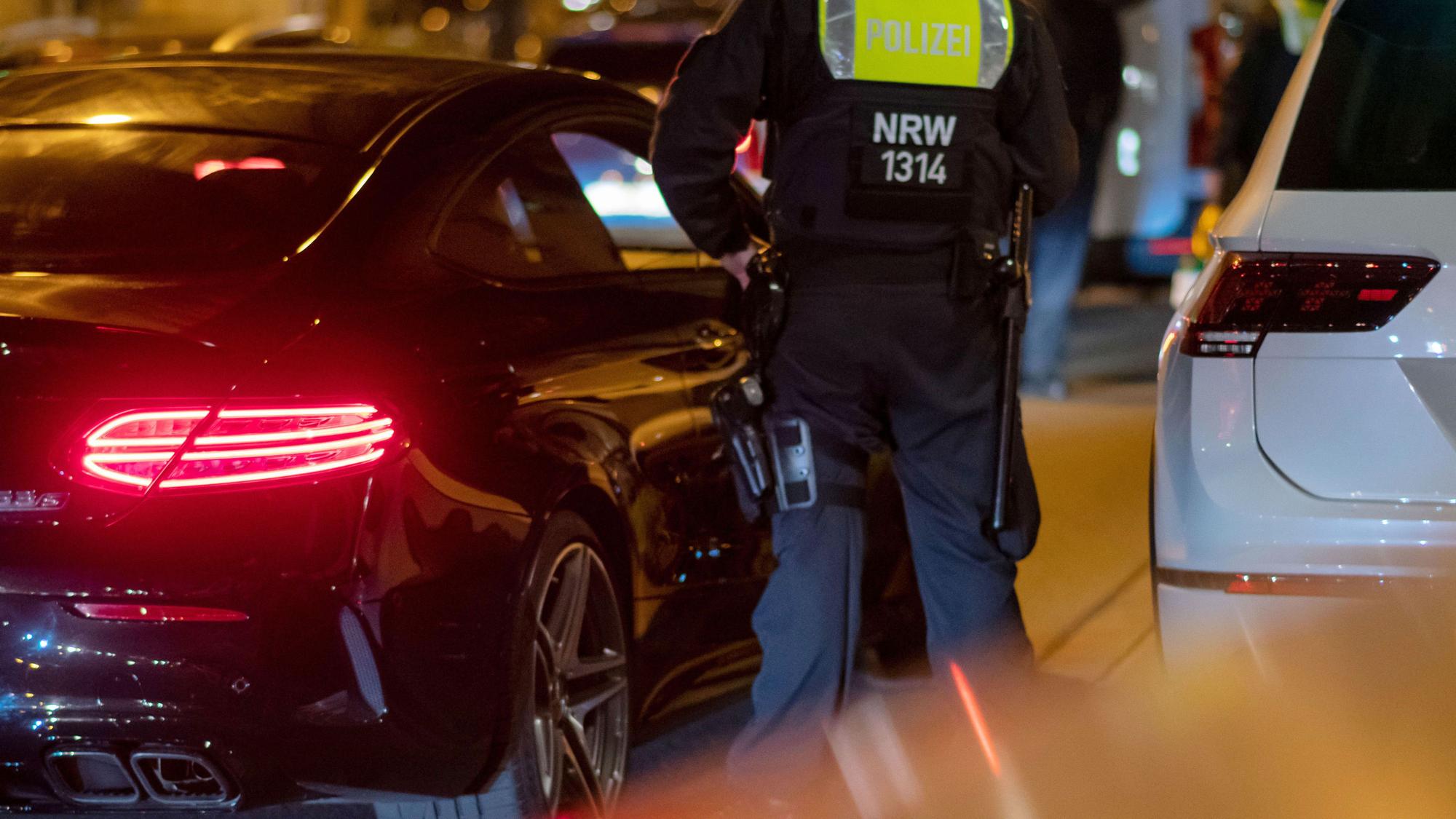 Ein Polizist steht an einem Pkw.