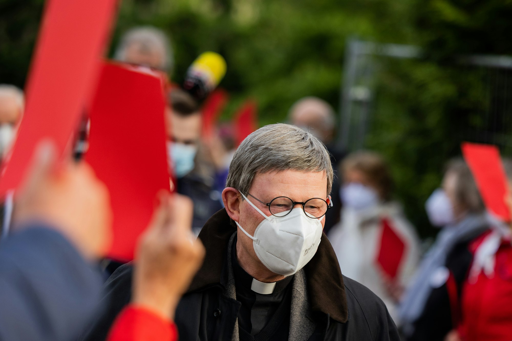 Kardinal Rainer Maria Woelki, Erzbischof von Köln, geht durch einen Spalier aus Gemeindemitgliedern, die ihm die Rote Karte zeigen.
