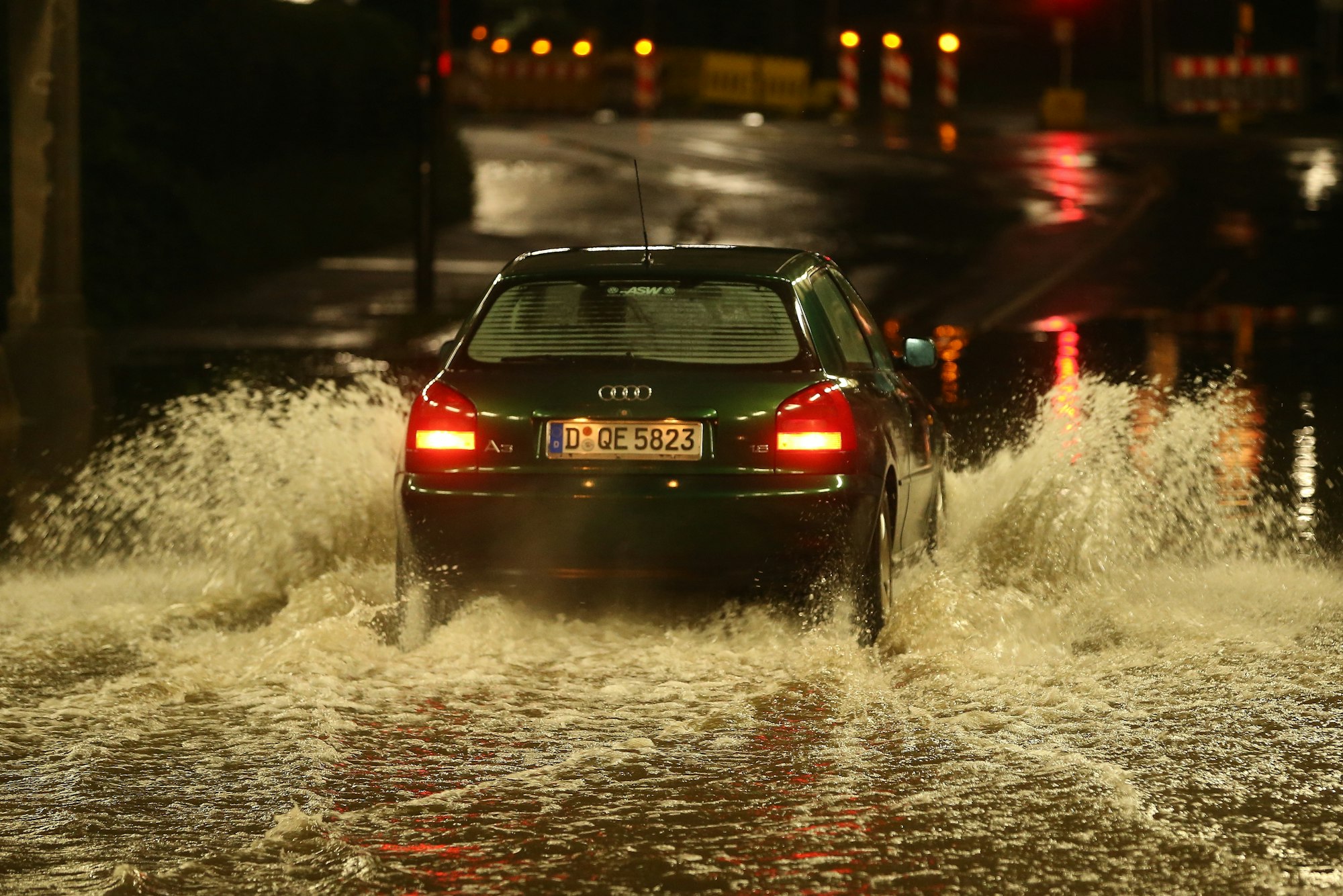 Ein PKW fährt durch eine nach Starkregen überflutete Bahnunterführung.
