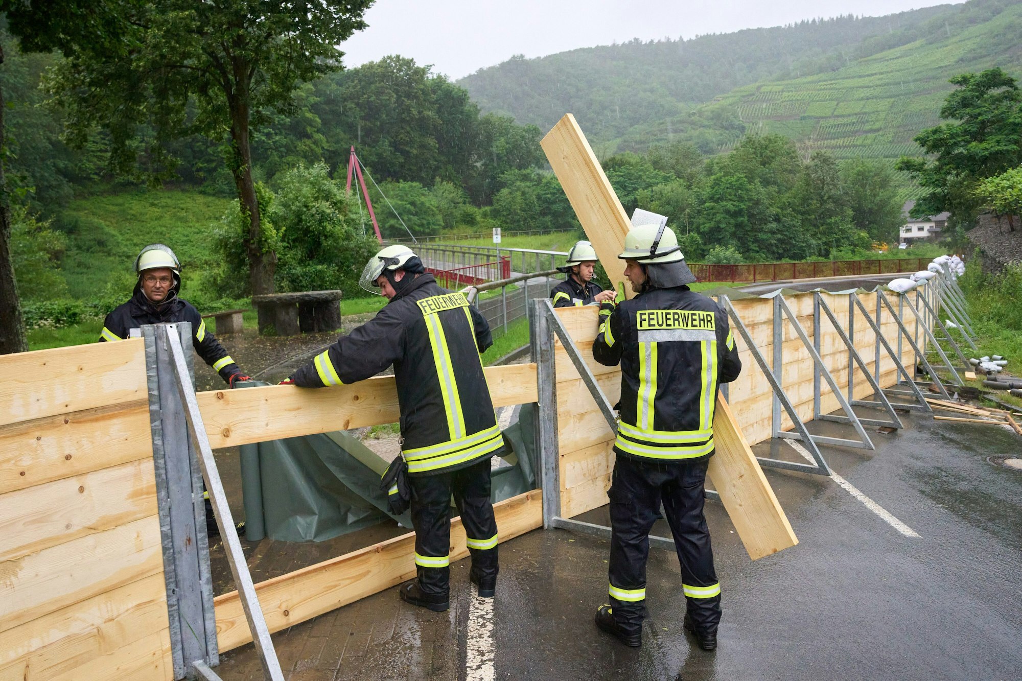 Feuerwehrleute errichten auf einer Straße eine Sperrwand aus Holz.