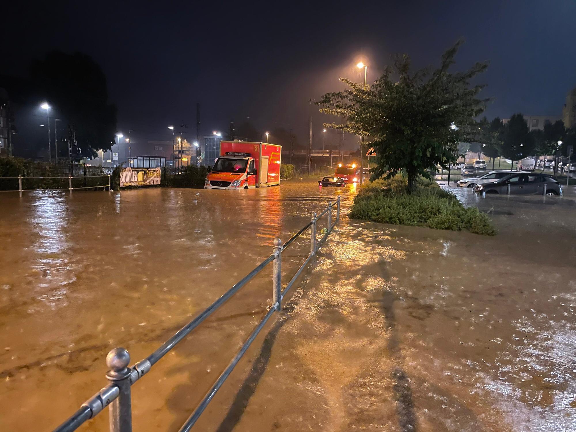 Autos und ein Rettungswagen sind auf einer überfluteten Straße zu sehen.