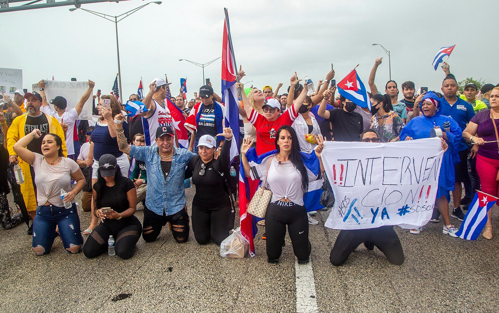 Mehrere Menschen versammeln sich in Miami (USA) mit Fahnen von Kuba und Postern auf dem Palmetto Expressway am Coral Way zur Unterstützung der Demonstranten in Kuba. Sie sind symbolisch auf die Knie gegangen.