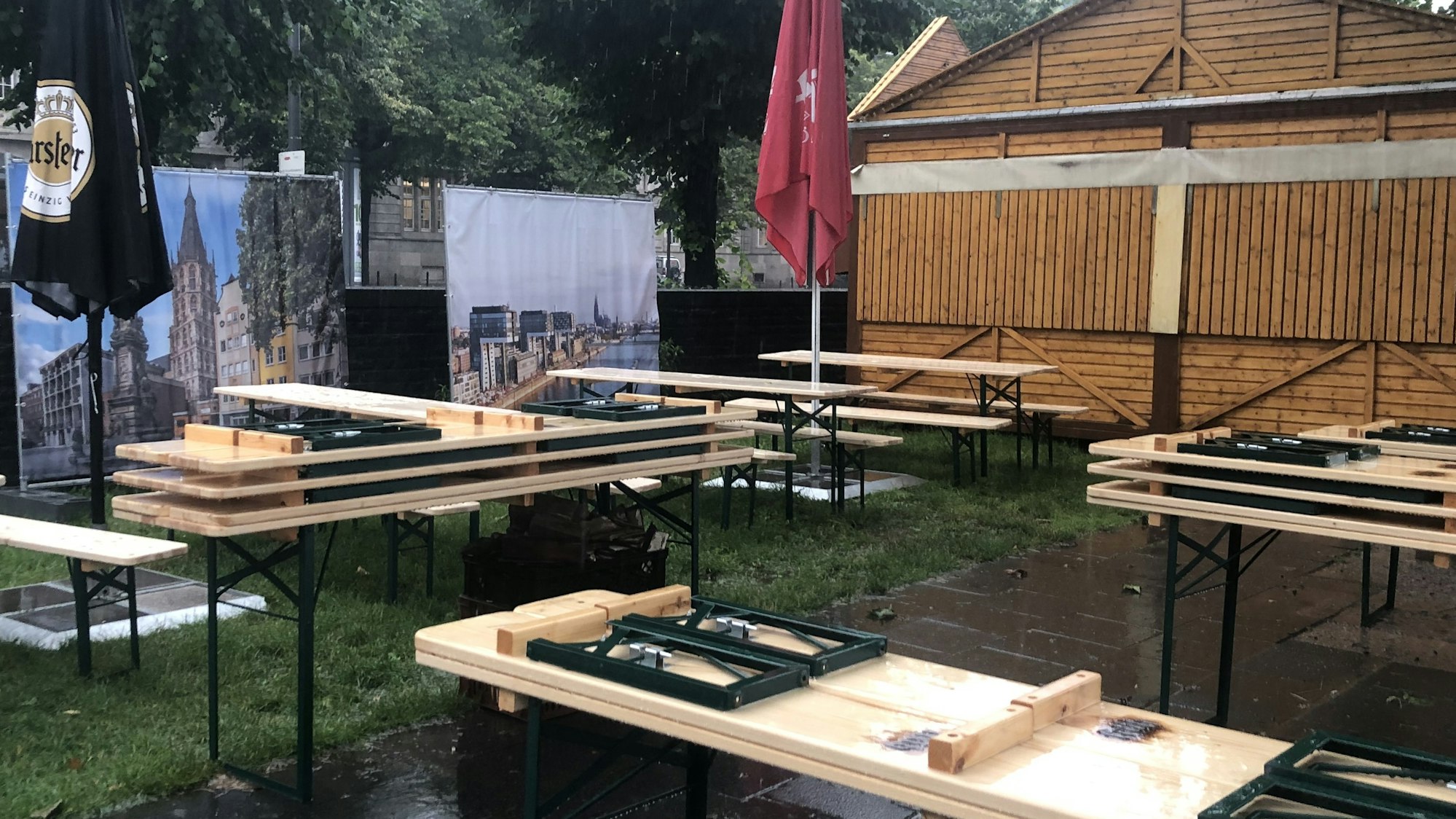 Die Bierbänke und Schirme im Pop-up Biergarten sind im Regen zusammengestellt und die Ausschankhütte geschlossen.