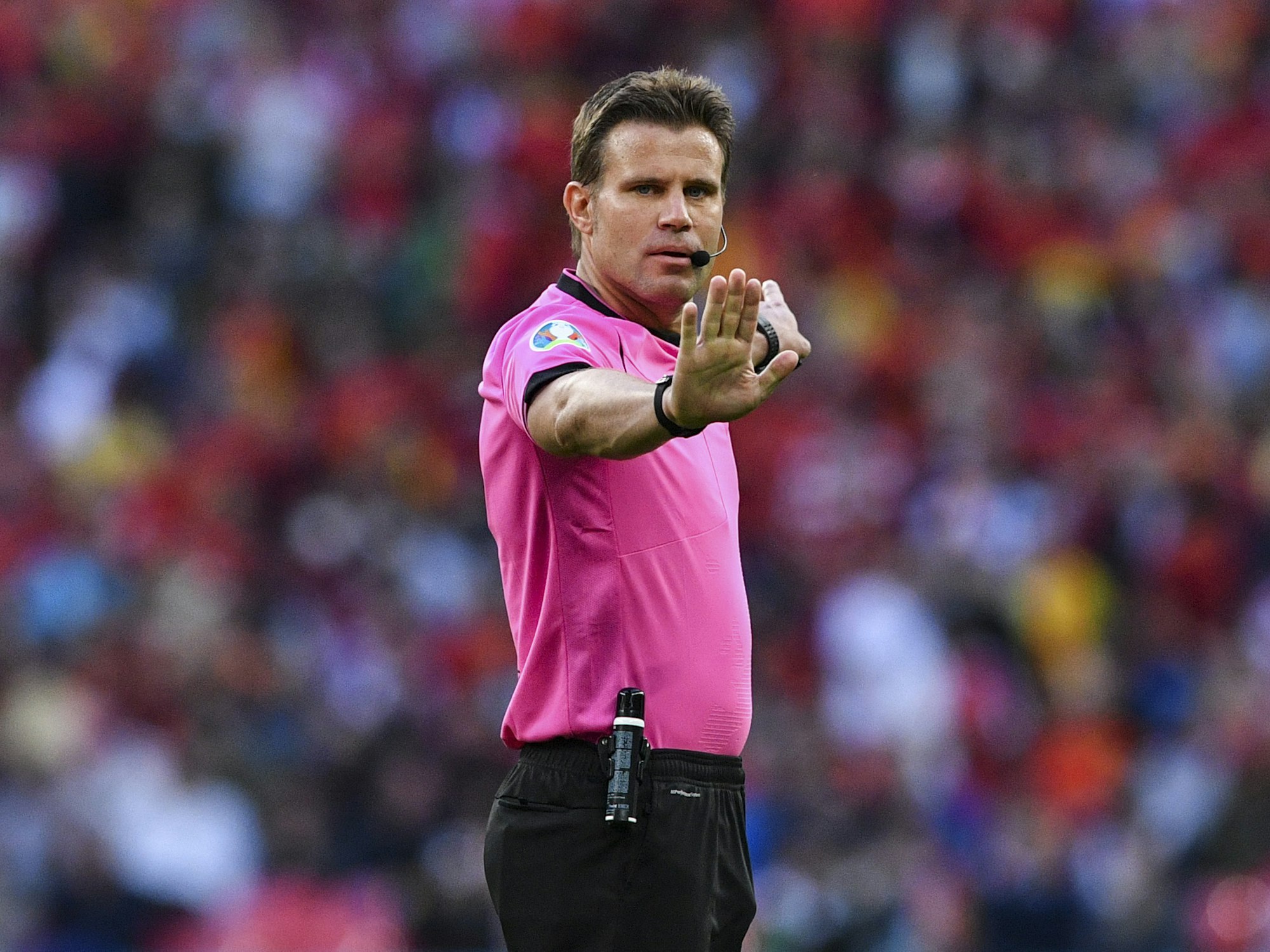 Felix Brych zeigt mit der Hand an, zu warten