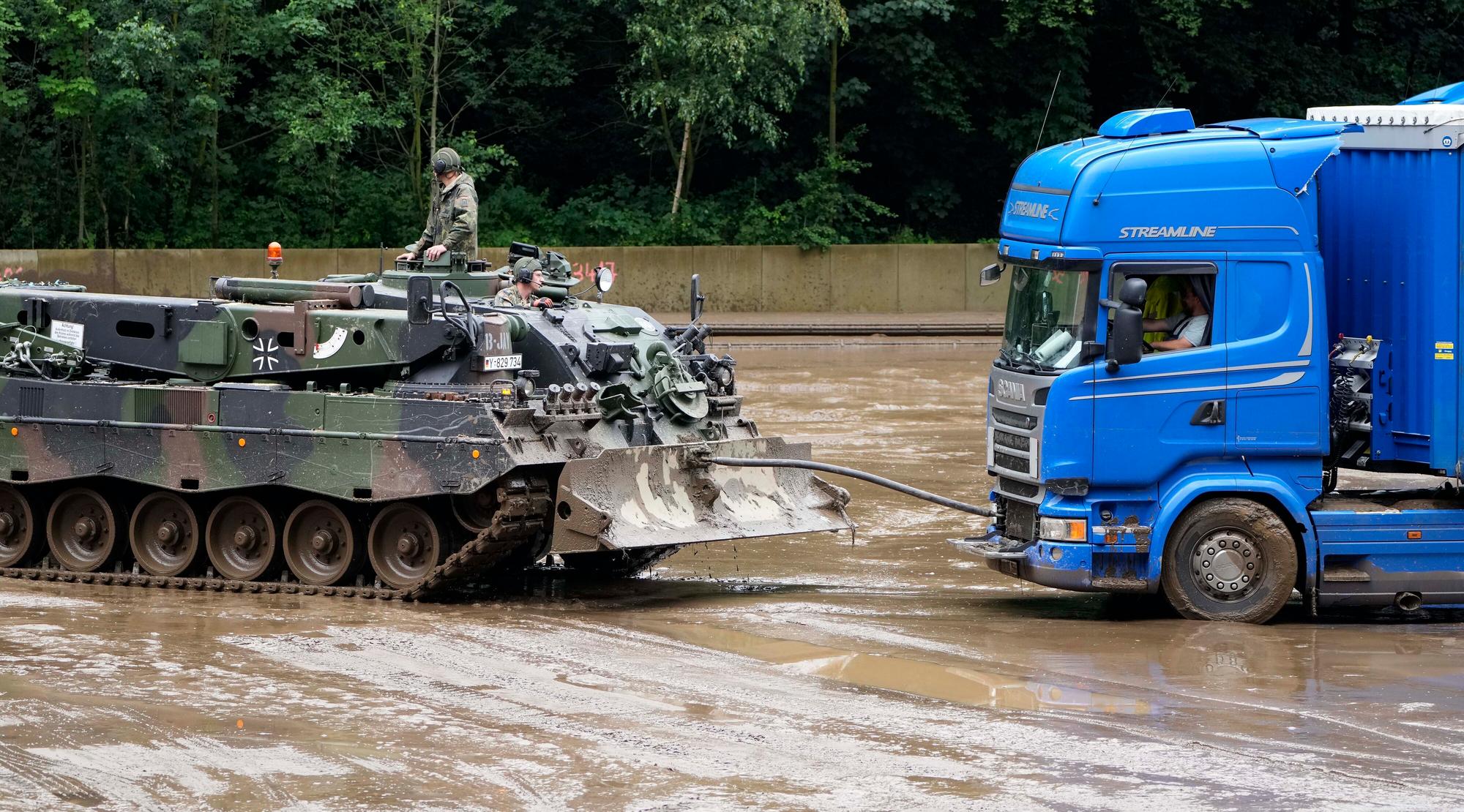 Ein Panzer der Bundeswehr zieht am Donnerstag (15. Juli) einen Lkw in Hagen aus dem Schlamm, nachdem es dort zu Überschwemmungen kam. Die Bundeswehr unterstützt die Hilfs- und Aufräumarbeiten in der Region.