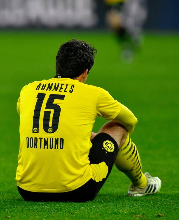 Mats Hummels sitzt auf dem Rasen mit den Armen auf den Knien gestützt