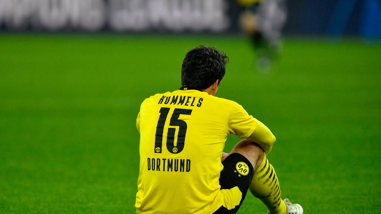 Mats Hummels sitzt auf dem Rasen mit den Armen auf den Knien gestützt