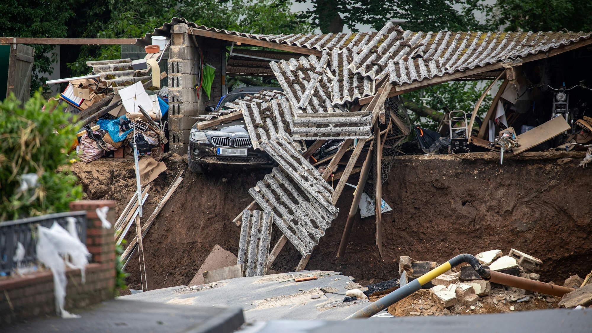 Ein Auto hängt im Ortsteil Blessem über einem Abgrund. Starkregen hatte am Mittwoch (14. Juli 2021) zu schweren Überschwemmungen und Hochwasser geführt.