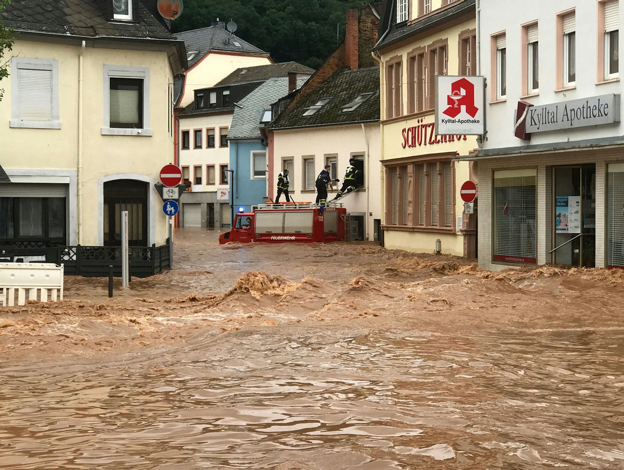 Feuerwehrmänner stehen auf einem Einsatzwagen, der in den Fluten steht.