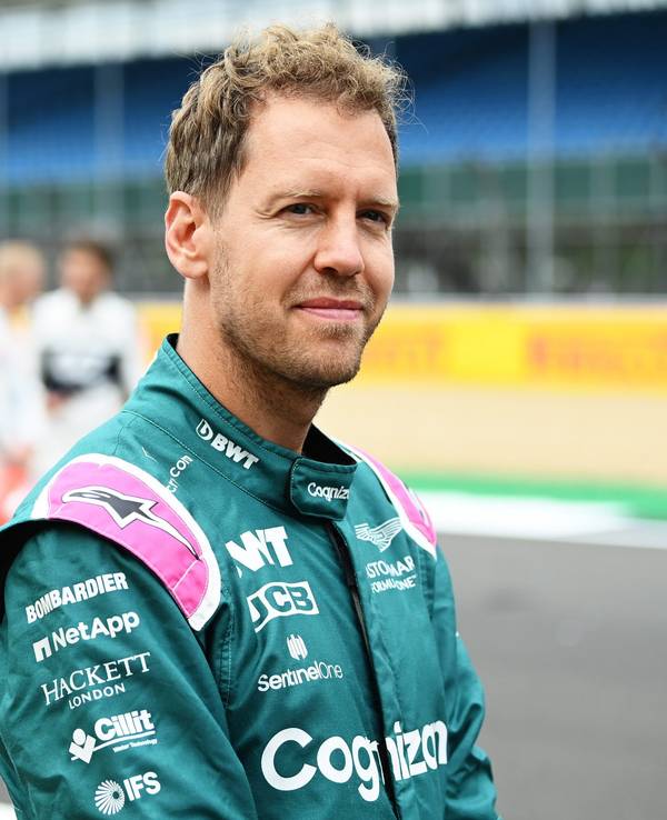 Sebastian Vettel lächelt auf der Rennstrecke der Formel 1 in Silverstone in die Kamera.