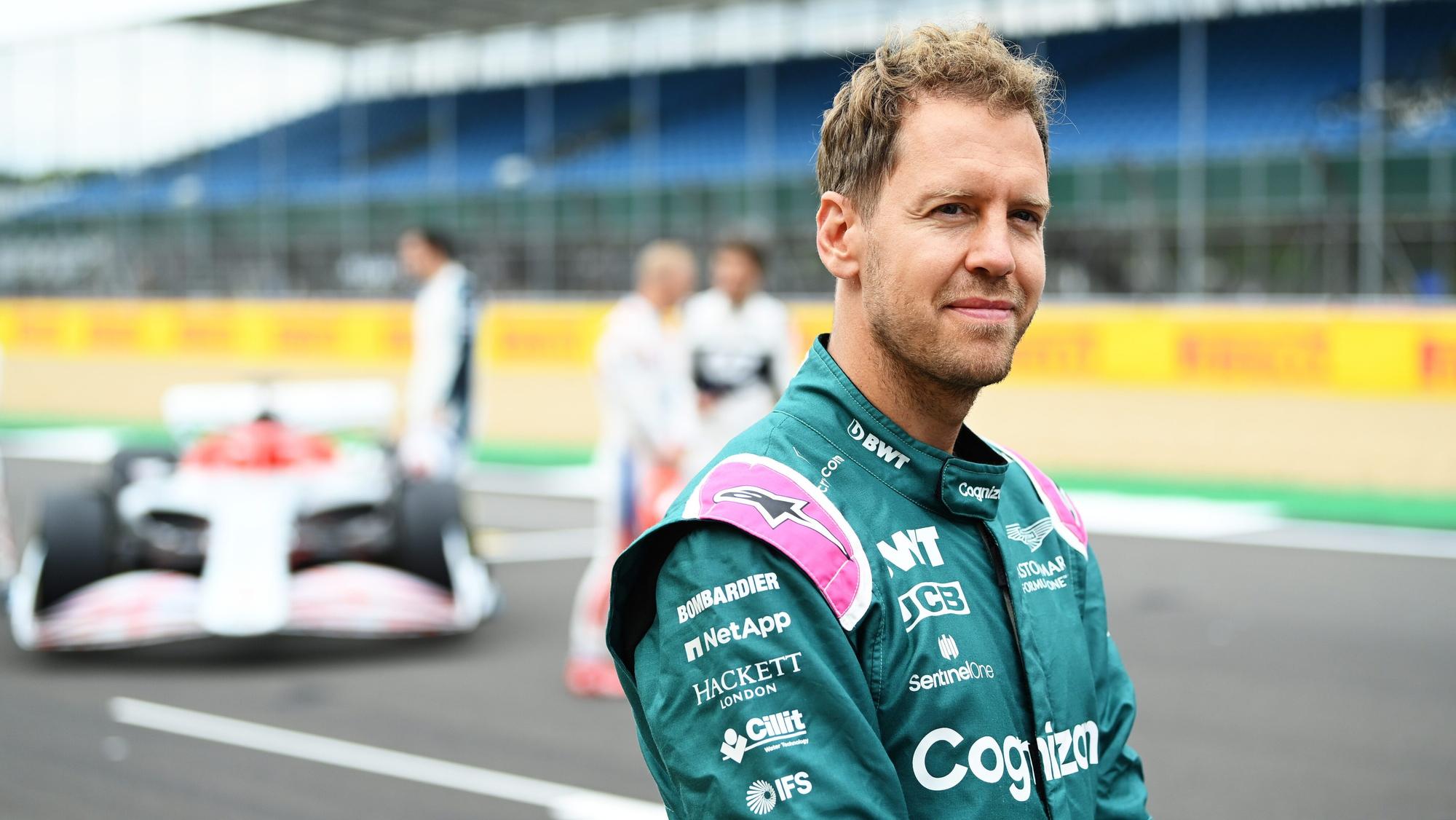 Sebastian Vettel lächelt auf der Rennstrecke der Formel 1 in Silverstone in die Kamera.