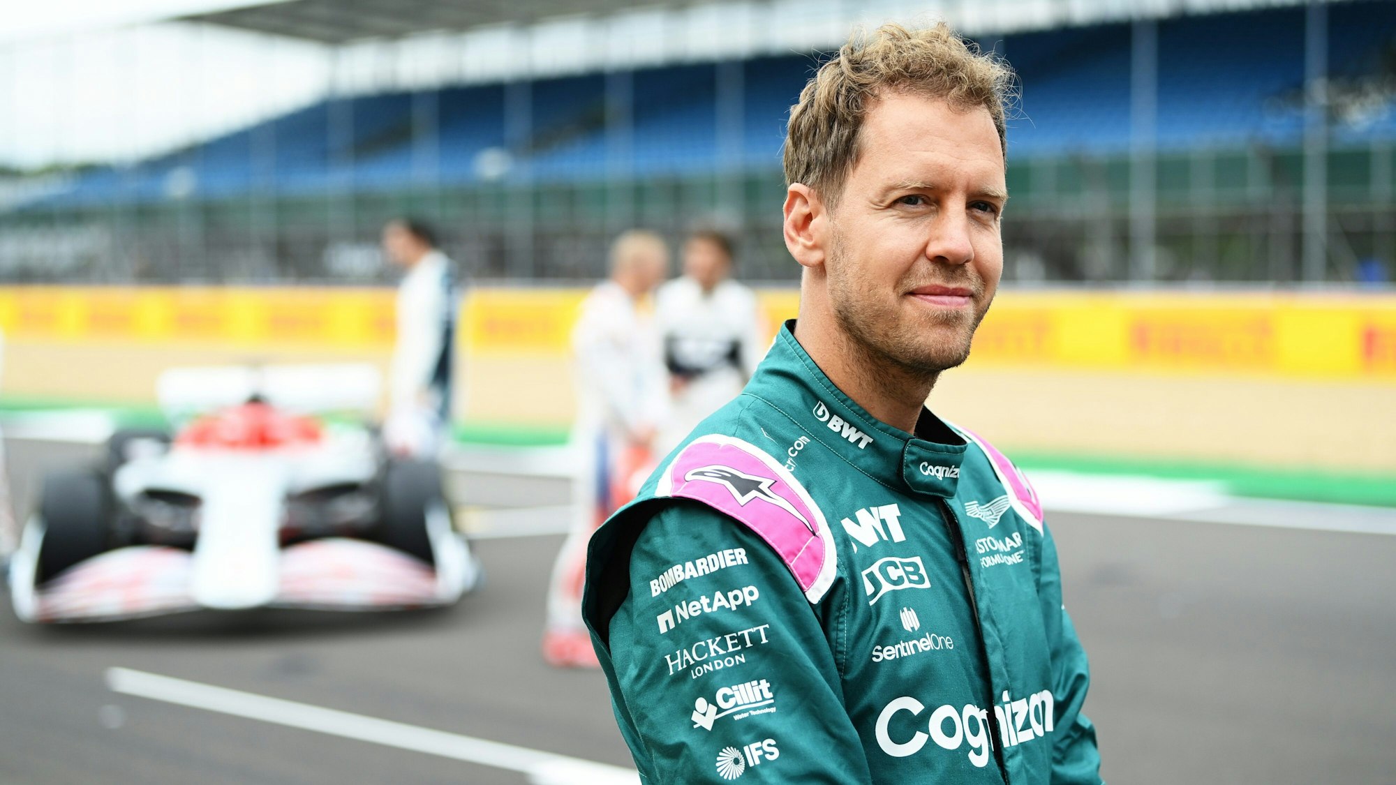 Sebastian Vettel lächelt auf der Rennstrecke der Formel 1 in Silverstone in die Kamera.