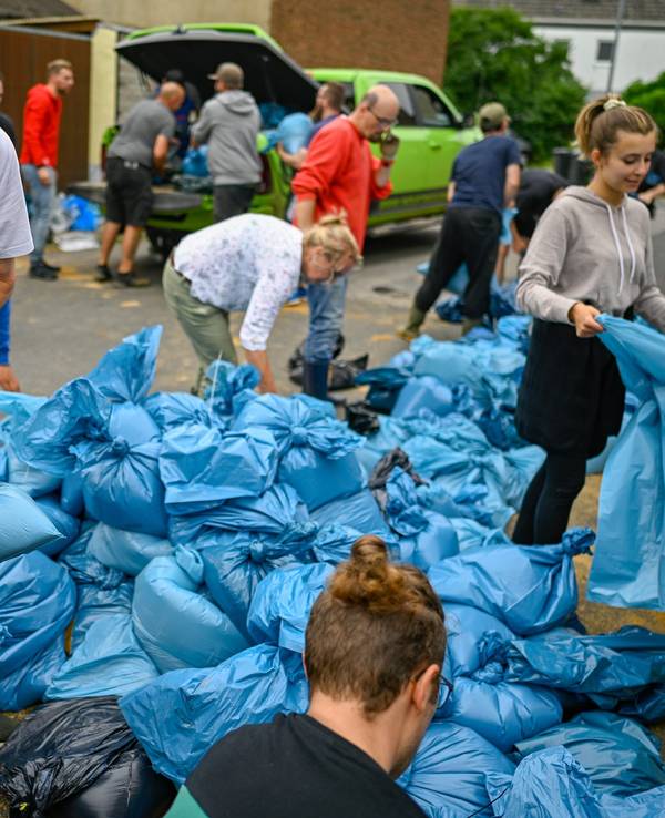In Erftstadt füllen Freiwillige am 16. Juli 2021 Tüten mit Sand.