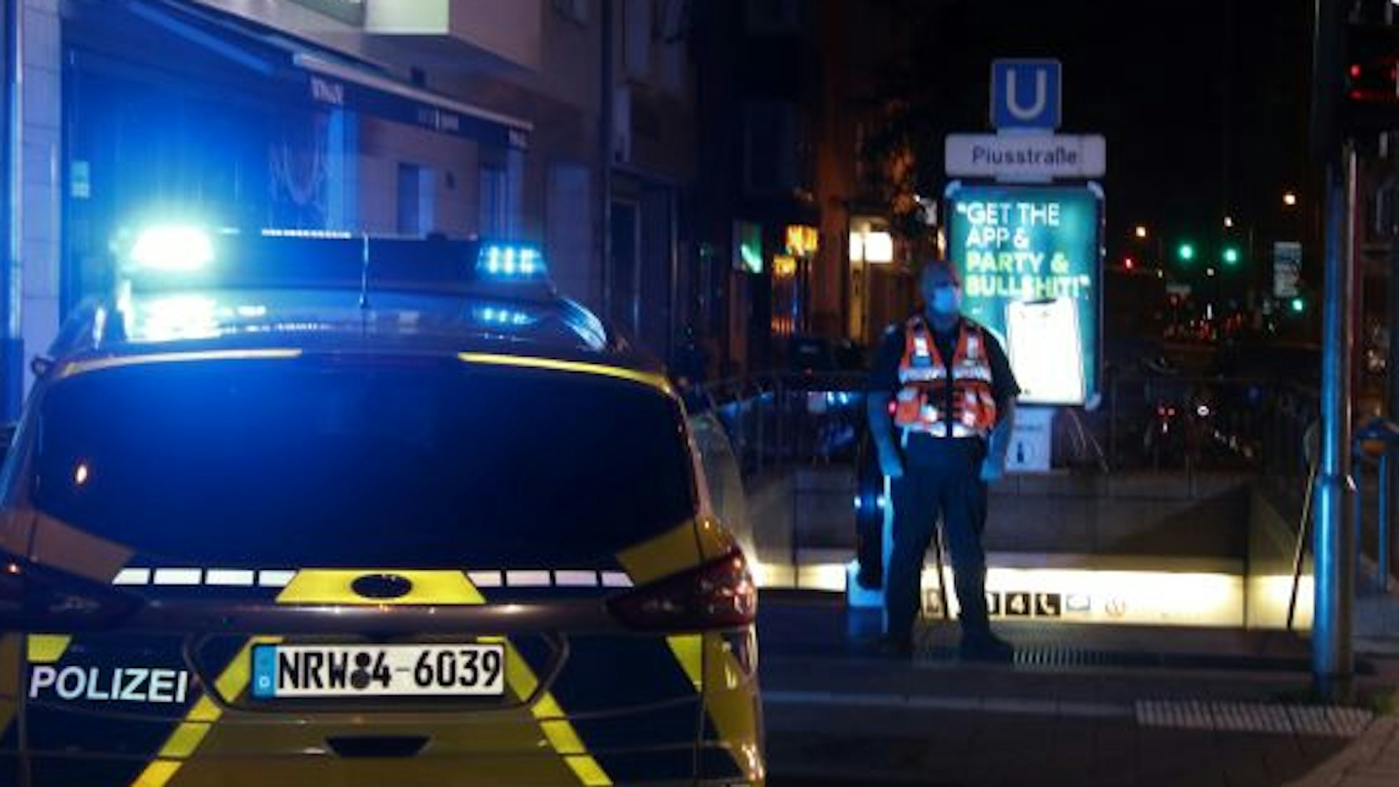 Ein Streifenwagen und ein Beamter stehen am Abgang zur U-Bahnhaltestelle Piusstraße.