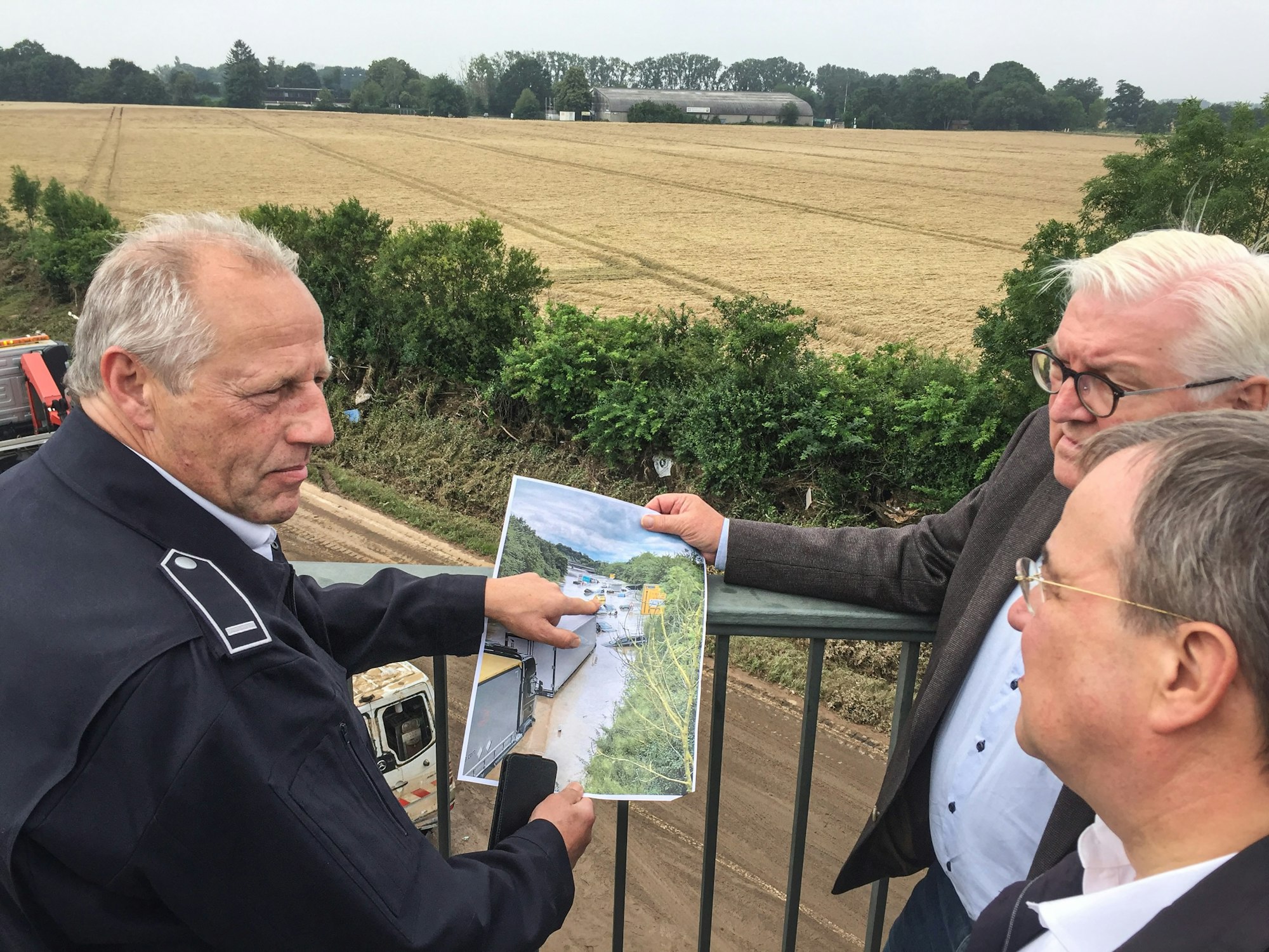Feuerwehrmann Udo Milewski (links) erklärt NRW-Ministerpräsident Armin Laschet (vorne) und Bundespräsident Frank-Walter Steinmeier an der B265 im Ortsteil Liblar die Situation nach der Flutkatastrophe.