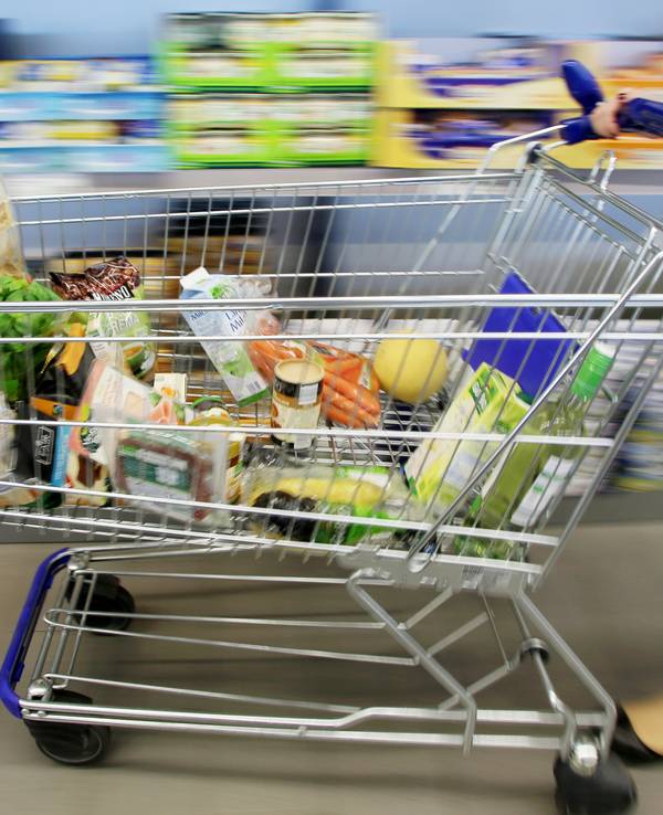 Kundin fährt gefüllten Einkaufswagen durch Aldi-Filiale.