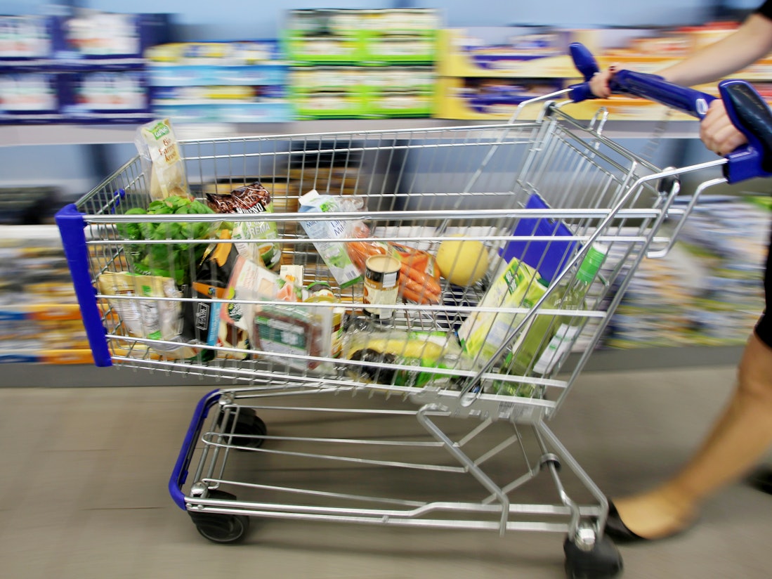 Kundin fährt gefüllten Einkaufswagen durch Aldi-Filiale.