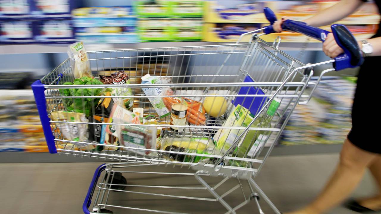 Kundin fährt gefüllten Einkaufswagen durch Aldi-Filiale.