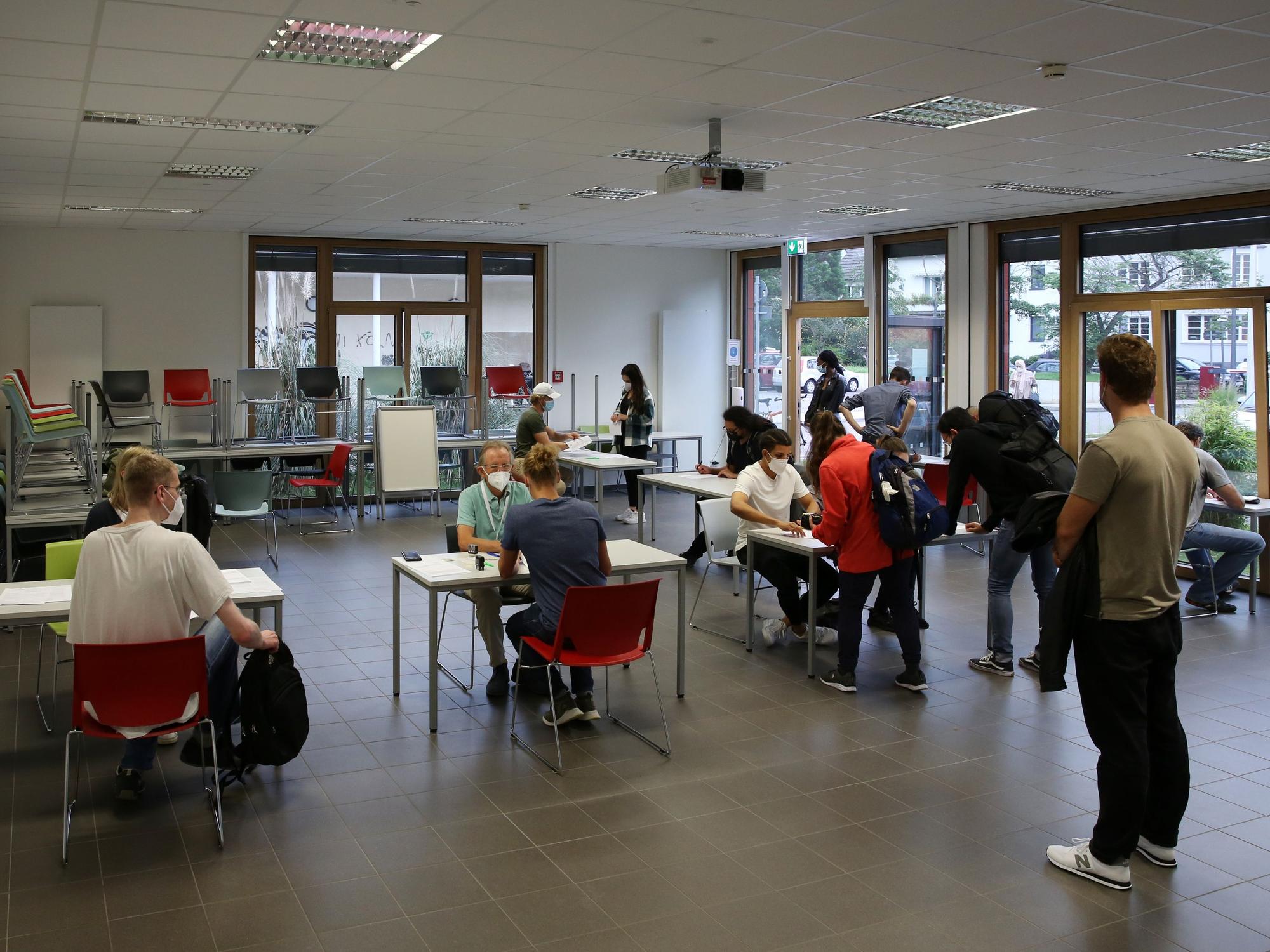 Studierende der Uni Köln warten in einem Raum auf ihre Impfung.