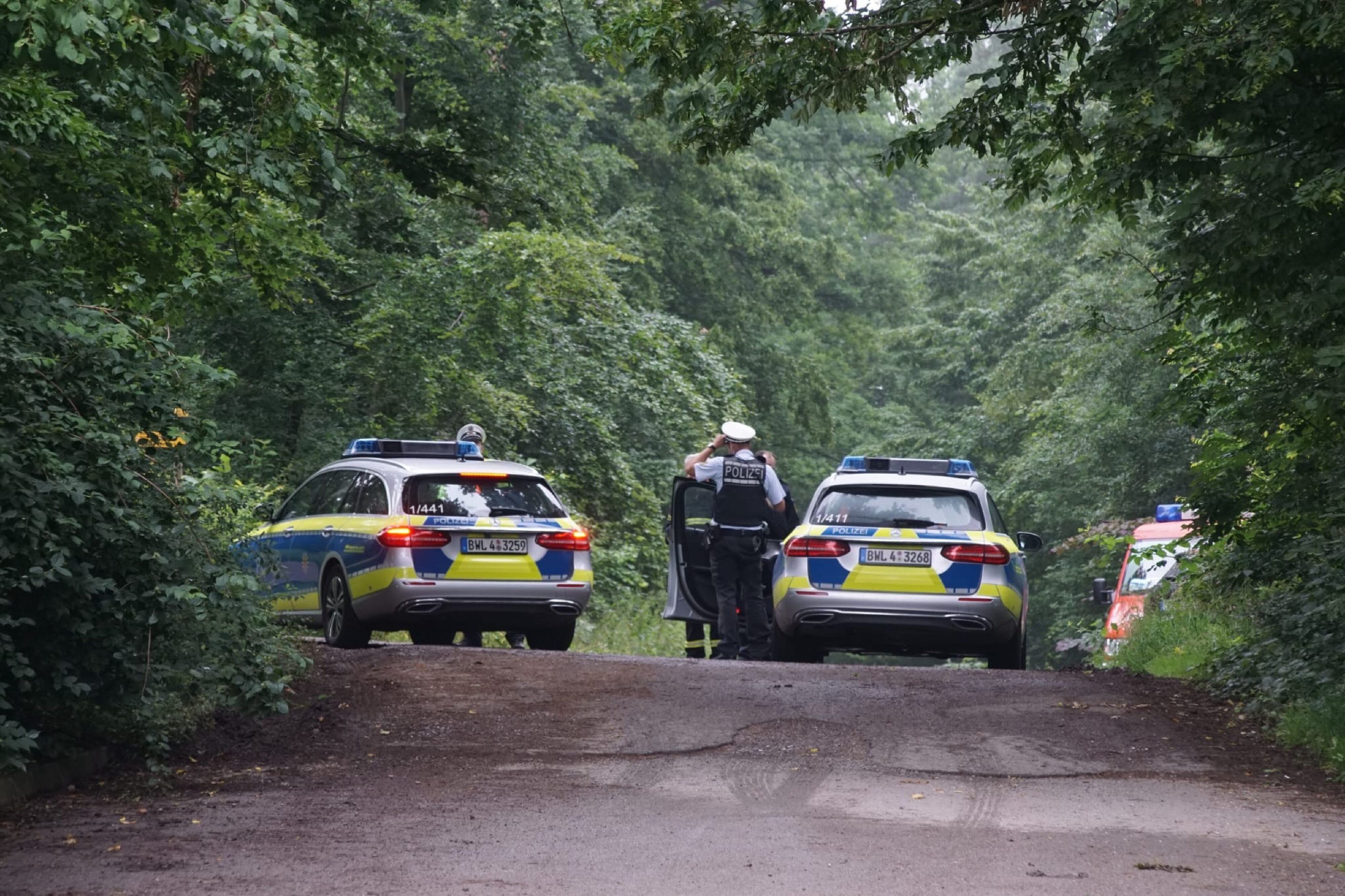 Polizeifahrzeuge stehen auf einer Straße, um die Zufahrt zum Unglücksort zu sperren.