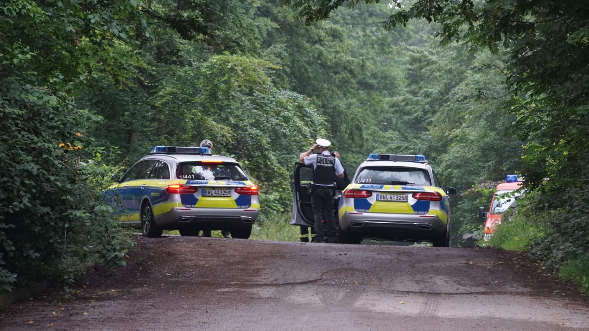 Polizeifahrzeuge stehen auf einer Straße, um die Zufahrt zum Unglücksort zu sperren.