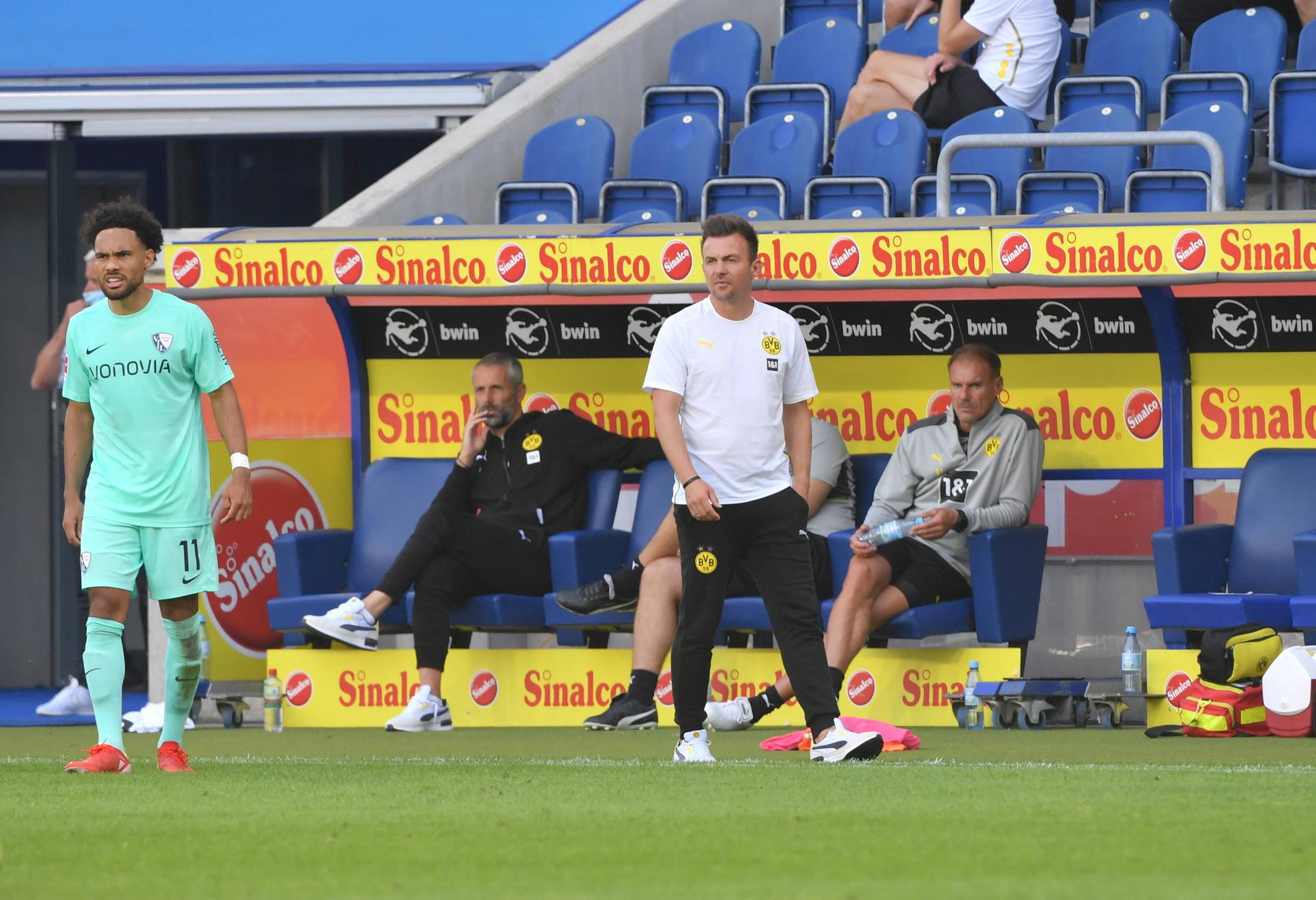 BVB U23-Trainer Enrico Maaßen an der Seitenlinie, Marco Rose sitzt im Hintegrund auf der Bank.