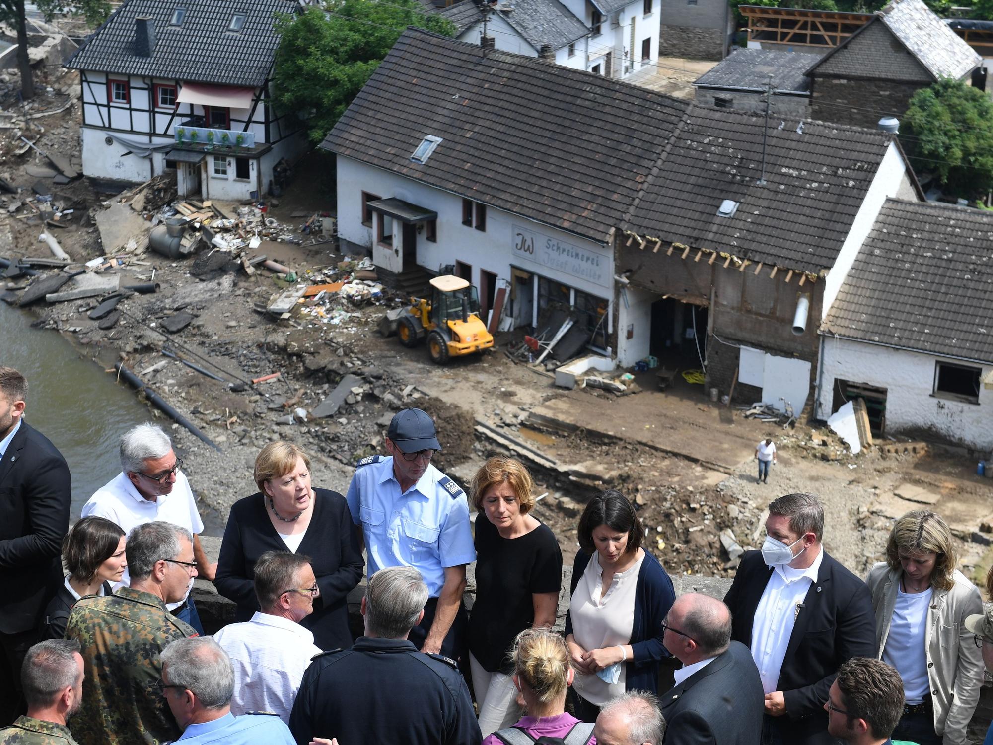 Bundeskanzlerin Angela Merkel (3.v.l.) und die rheinland-pfälzische Ministerpräsidentin Malu Dreyer (5.v.l.,SPD) stehen während ihres Besuchs in den vom Hochwasser betroffenen Gebieten auf einer Brücke.