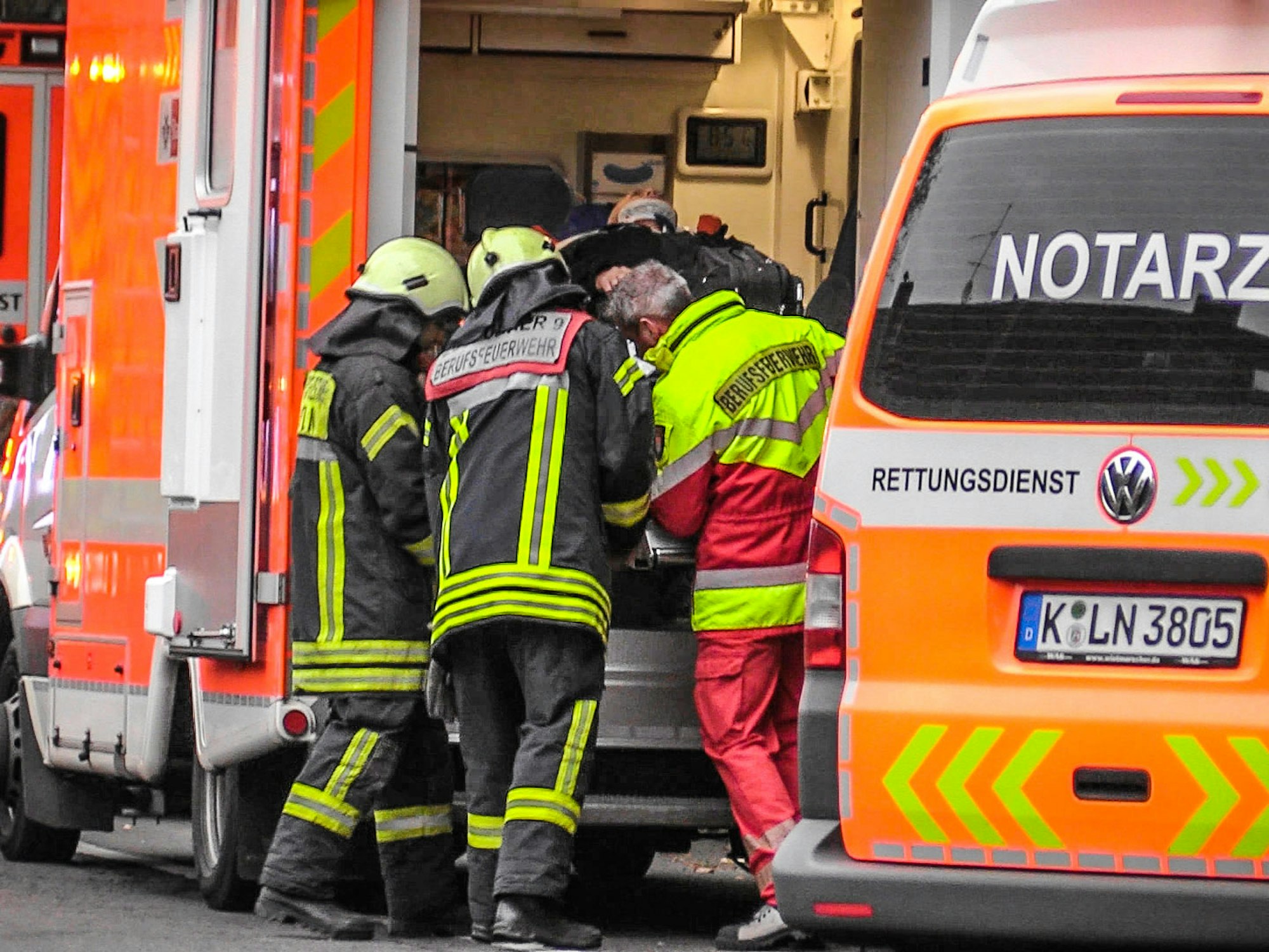 Drei Feuerwehrleute schieben eine verletzte Person in einen RTW.