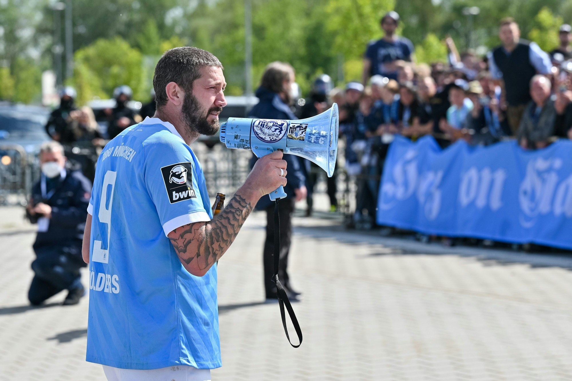 Sascha Mölders mit einem Megaphon in der Hand vor 1860-München-Fans.