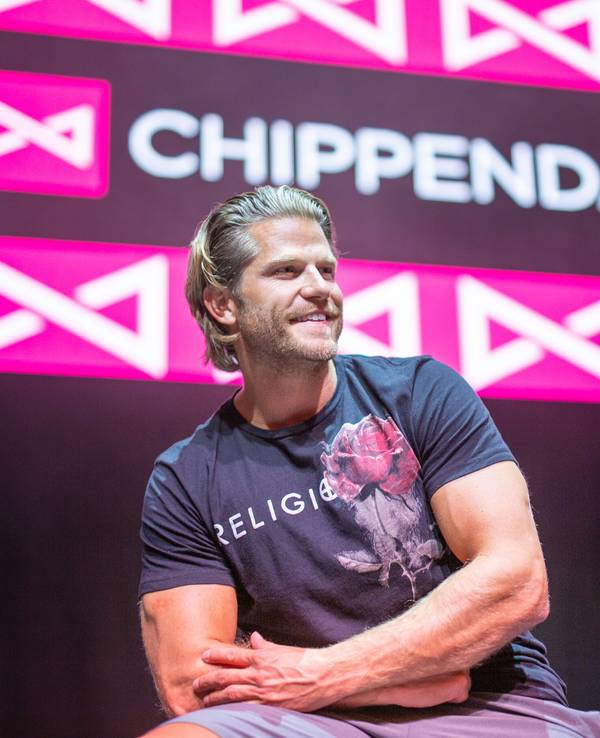 Paul Janke gibt es jetzt auf Onlyfans. Hier sitzt er in München vor dem Logo der Strippercombo Chippendales.