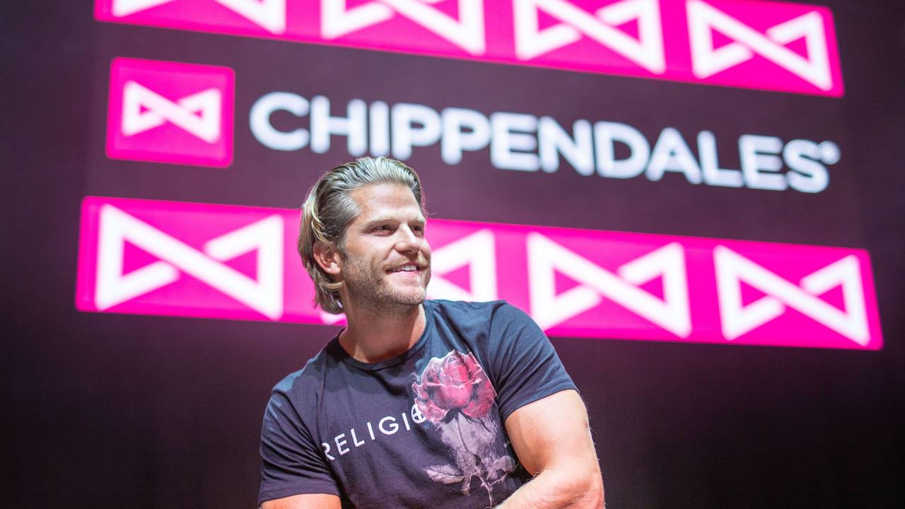 Paul Janke gibt es jetzt auf Onlyfans. Hier sitzt er in München vor dem Logo der Strippercombo Chippendales.