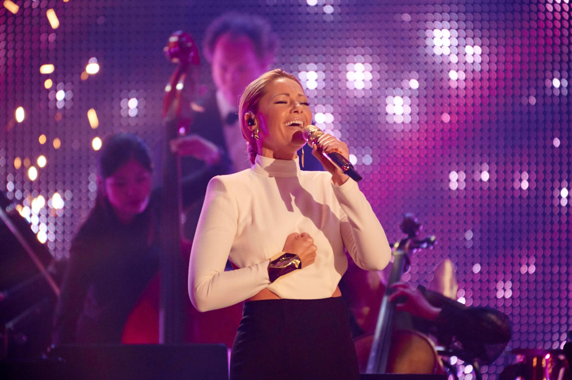 Helene Fischer singt beim RTL-Jahresrückblick mit Mikrofon in der Hand und ihrer Band im Hintergrund.