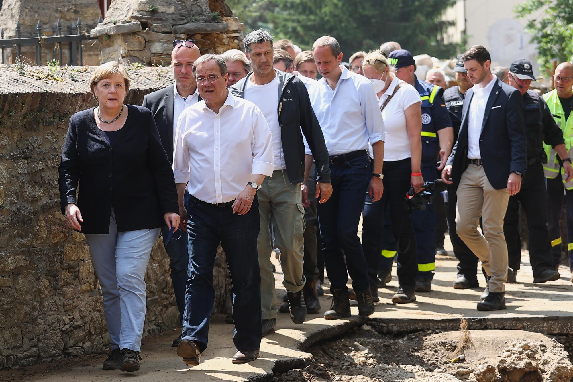 Bundeskanzlerin Angela Merkel (CDU, vorn links) und Armin Laschet (CDU, vorn rechts), Ministerpräsident von Nordrhein-Westfalen, laufen durch dich zerstörten Straßen von Bad Münstereifel.