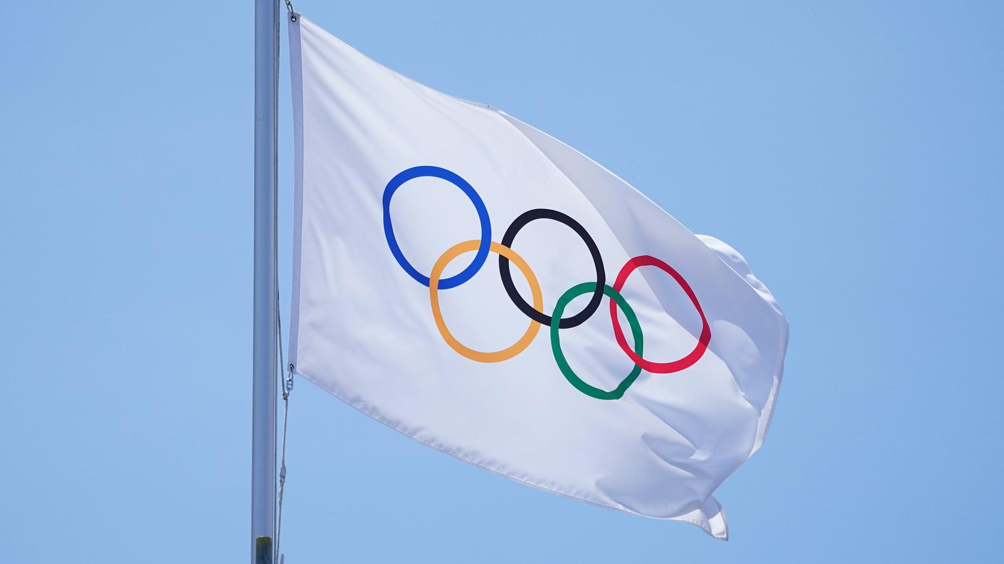Die olmpische Fahne mit den olympischen Ringen weht in Tokio an einem Fahnenmast.