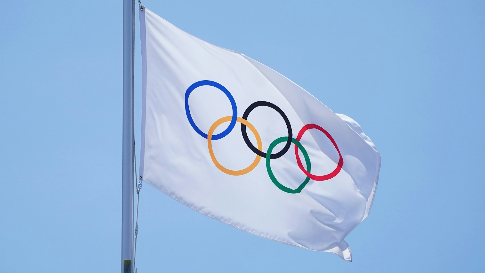 Die olmpische Fahne mit den olympischen Ringen weht in Tokio an einem Fahnenmast.