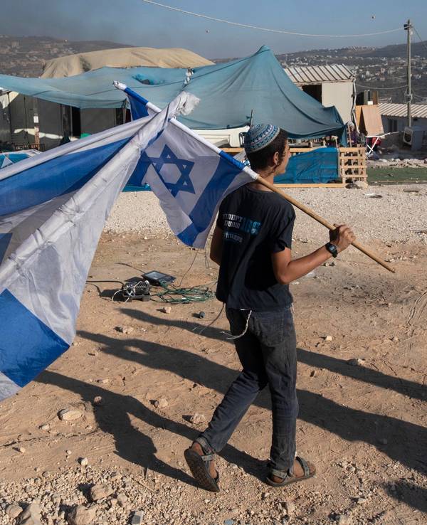 Zwei Menschen schwenken in einer Siedlung Israel-Flaggen im Westjordanland.