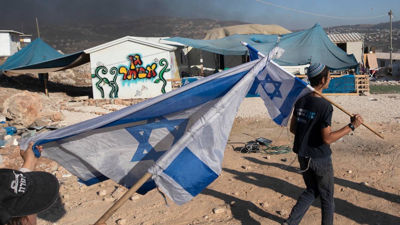 Zwei Menschen schwenken in einer Siedlung Israel-Flaggen im Westjordanland.
