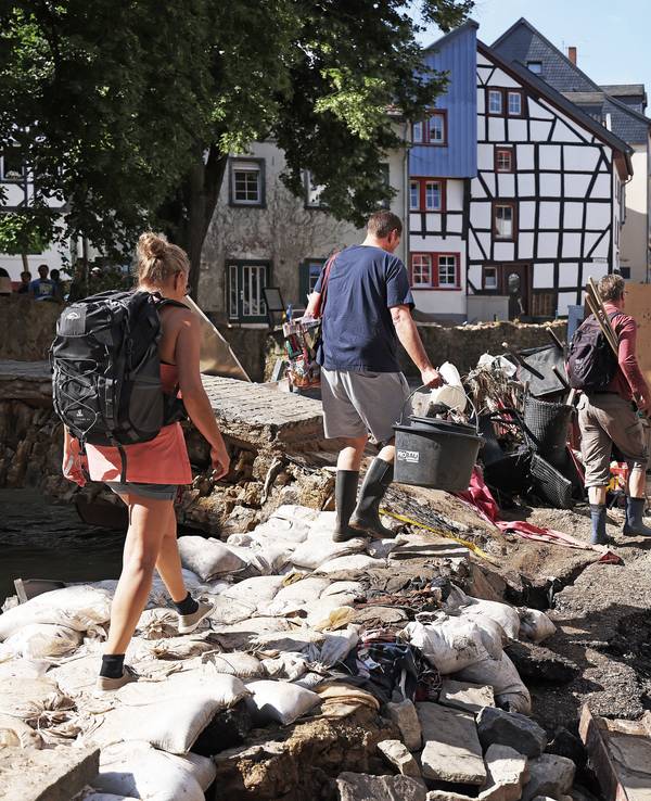 Helfer gehen durch den Ortskern. In Bad Münstereifel hat die über die Ufer getretene Erft erhebliche Schäden angerichtet.