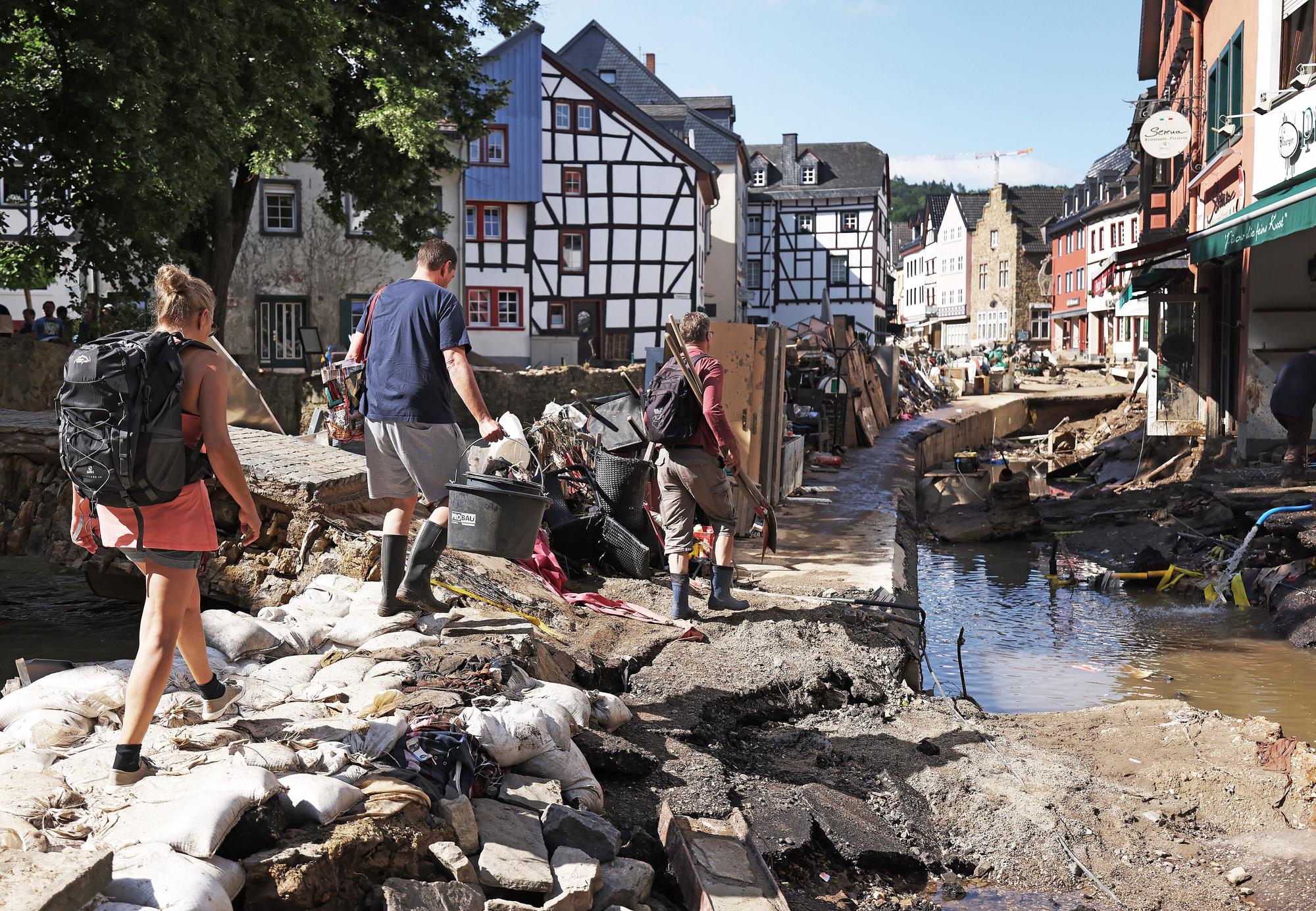 Helfer gehen durch den Ortskern. In Bad Münstereifel hat die über die Ufer getretene Erft erhebliche Schäden angerichtet.